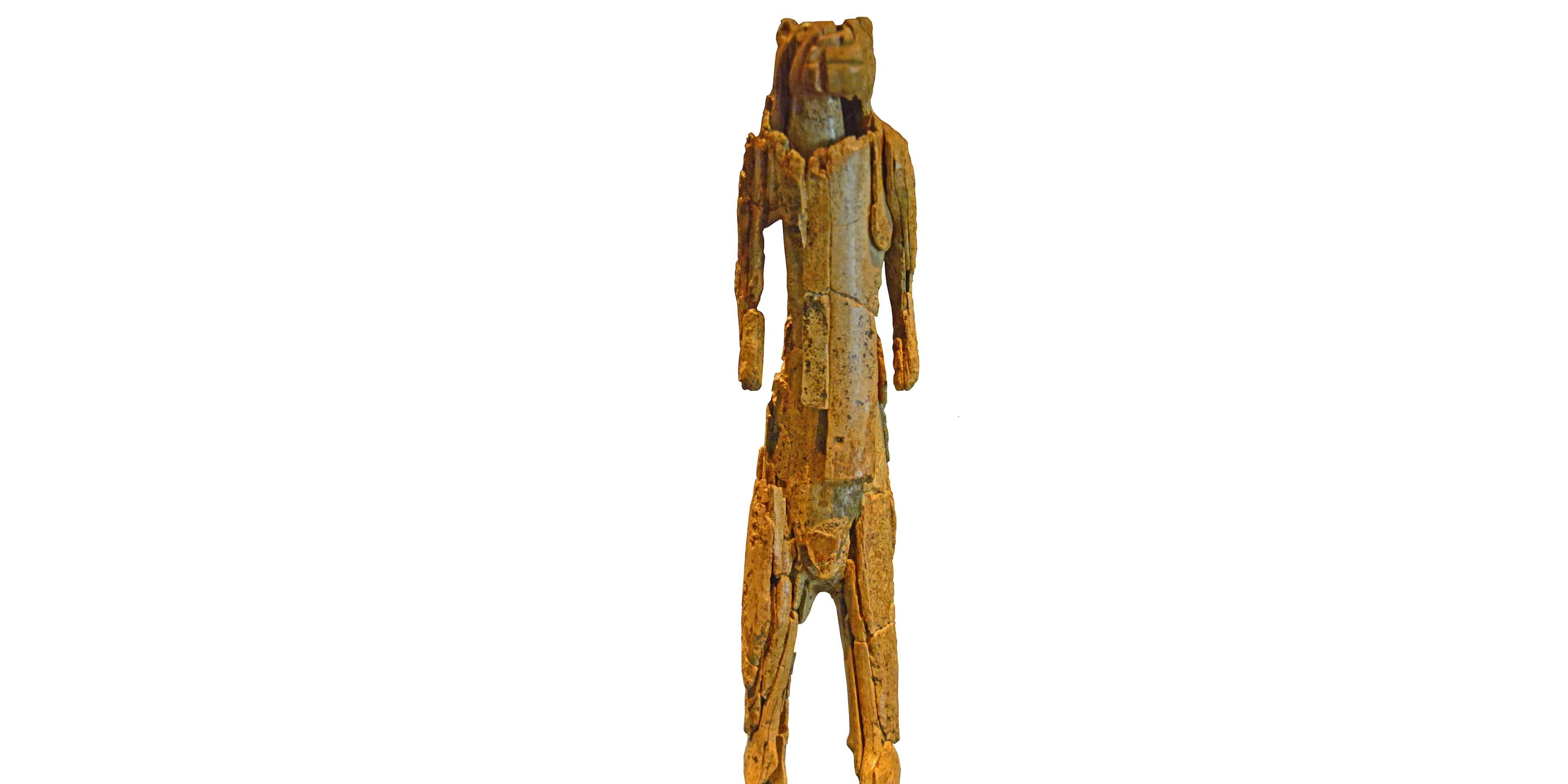 A weathered, wooden sculpture with a tall, slender form and a textured, organic appearance stands against a plain white background.
