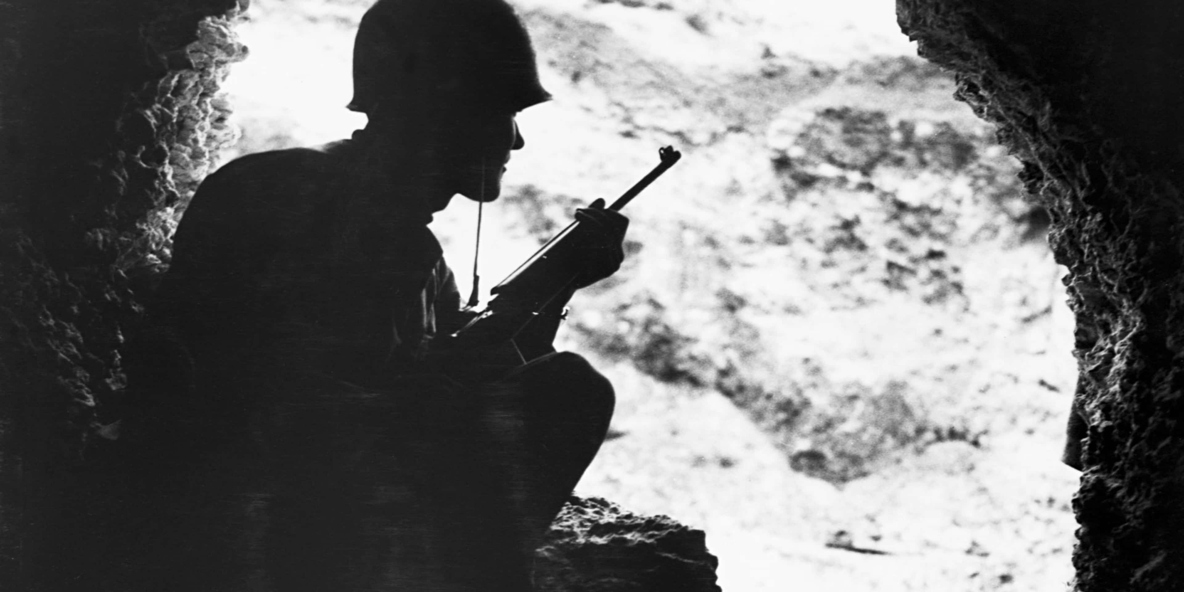 Okinawa hills, a Marine rifleman resorts to cat-and-mouse tactics to pick off enemy snipers in the surrounding ridges, June 1945