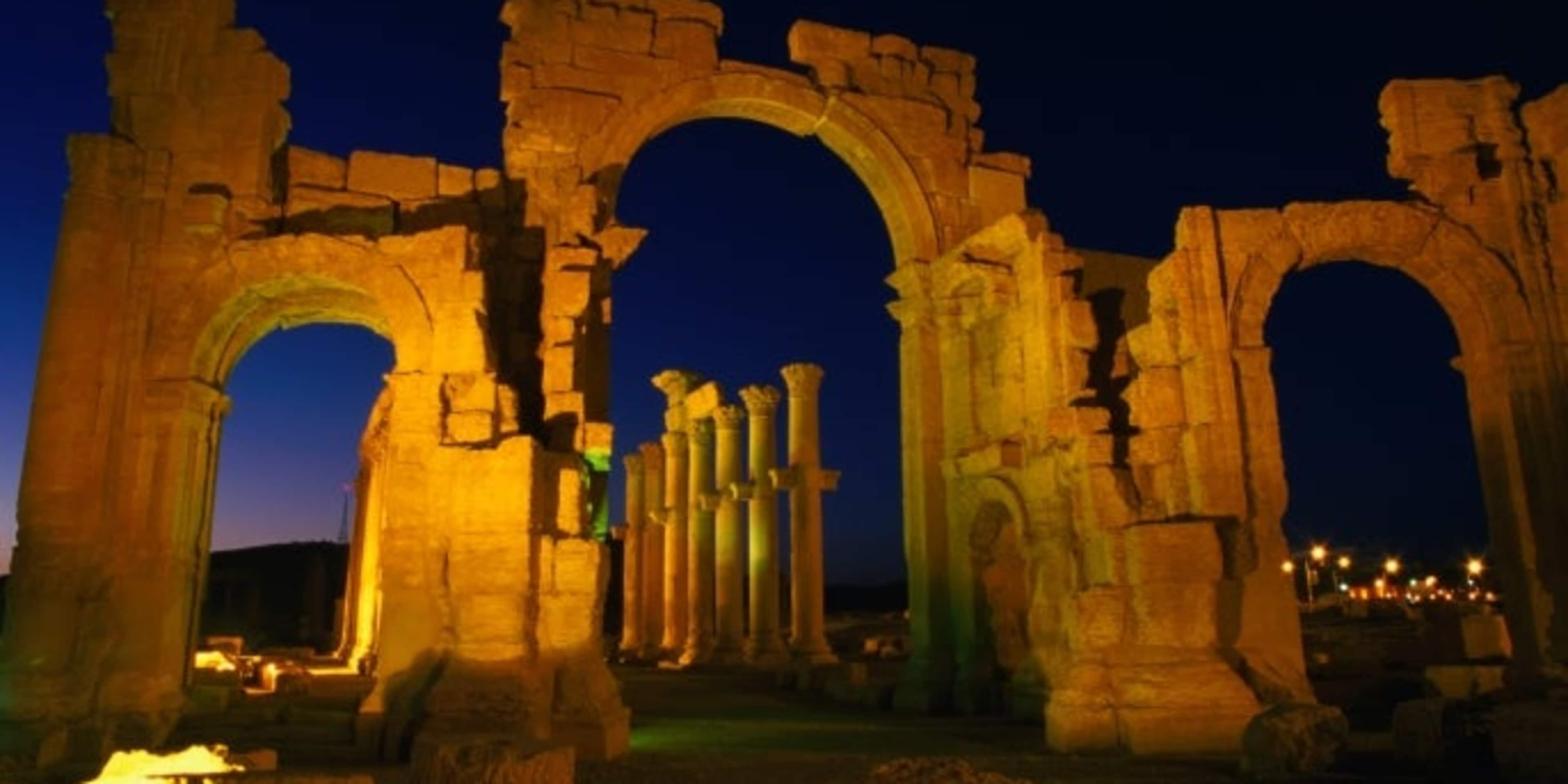 Floodlit monumental arch marking the entrance to Palmyra. (Credit: Mark Daffey / Getty Images)