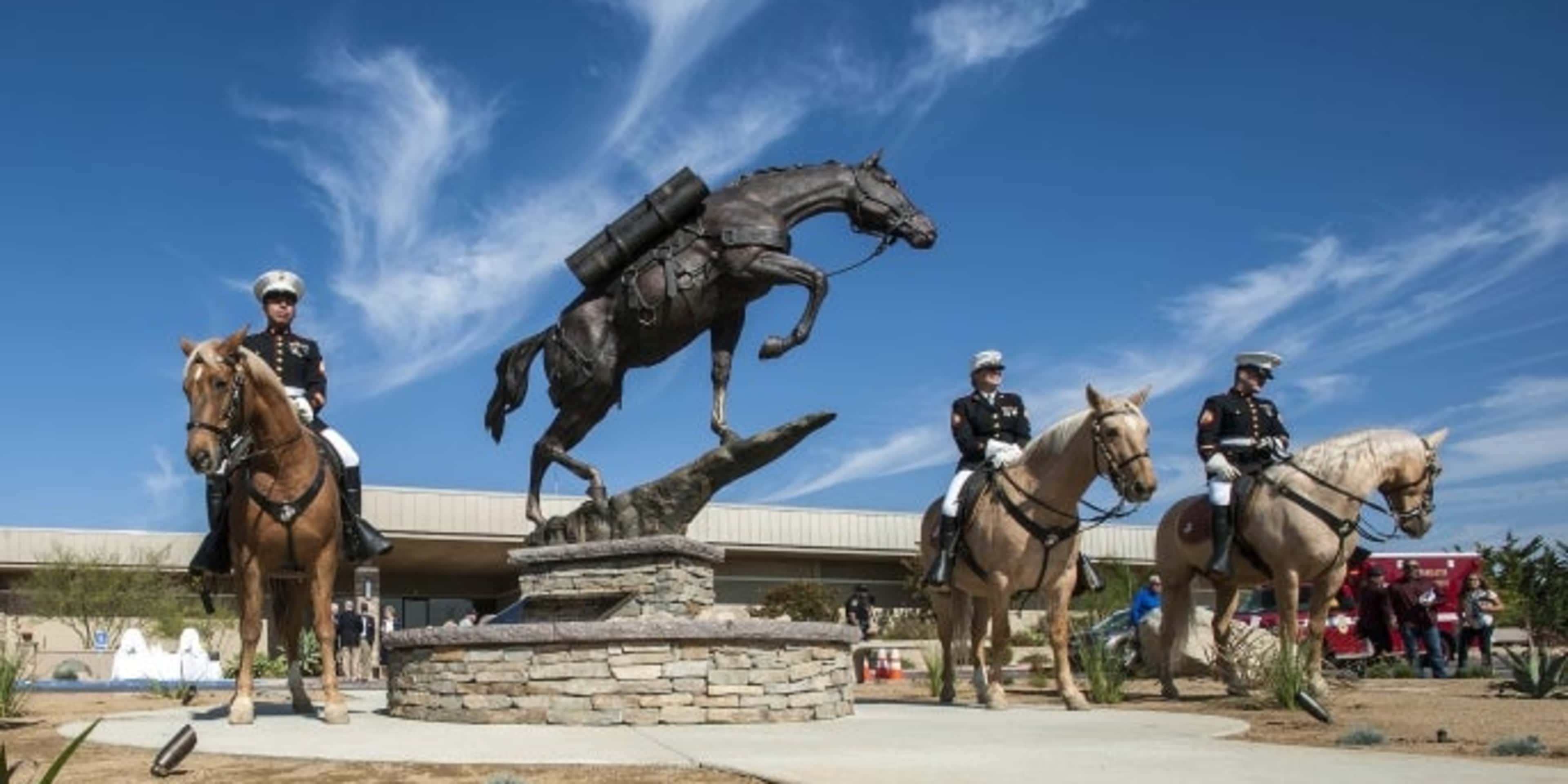 The Marine Corps Mounted Color Guard poses for photographs with the bronze statue of Staff Sergeant Reckless, a horse that served in the Korean War from Camp Pendleton, following a dedication ceremony at Camp Pendleton, 2016. (Credit: Mark Rightmire/The Orange County Register/SCNG via AP)