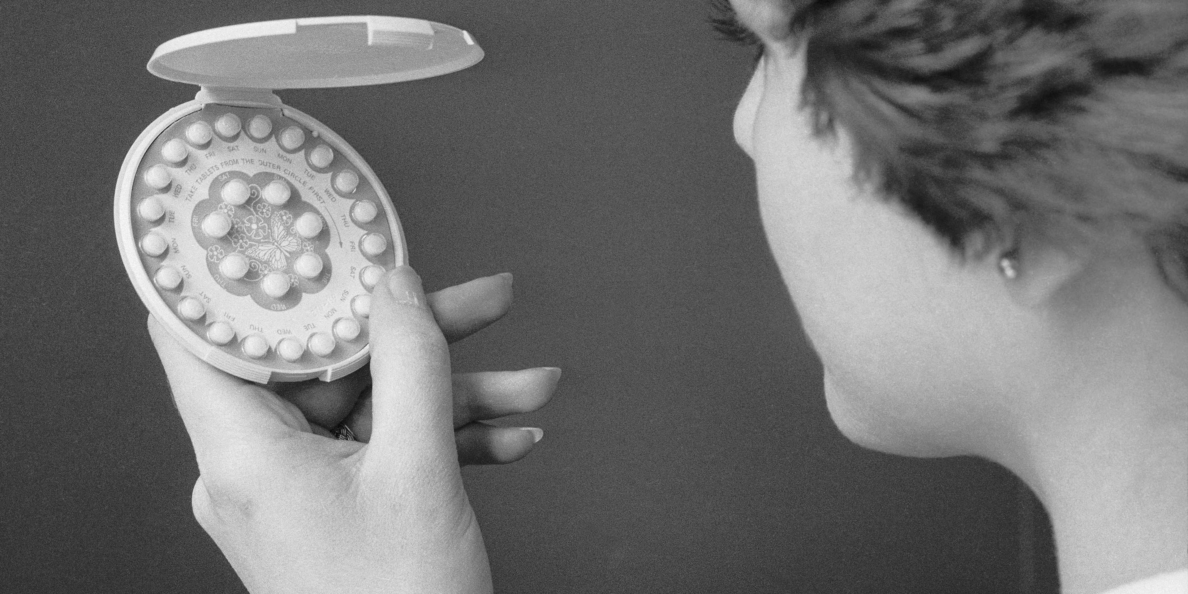 A 1976 photo of a woman holding a pack of birth control pills.
