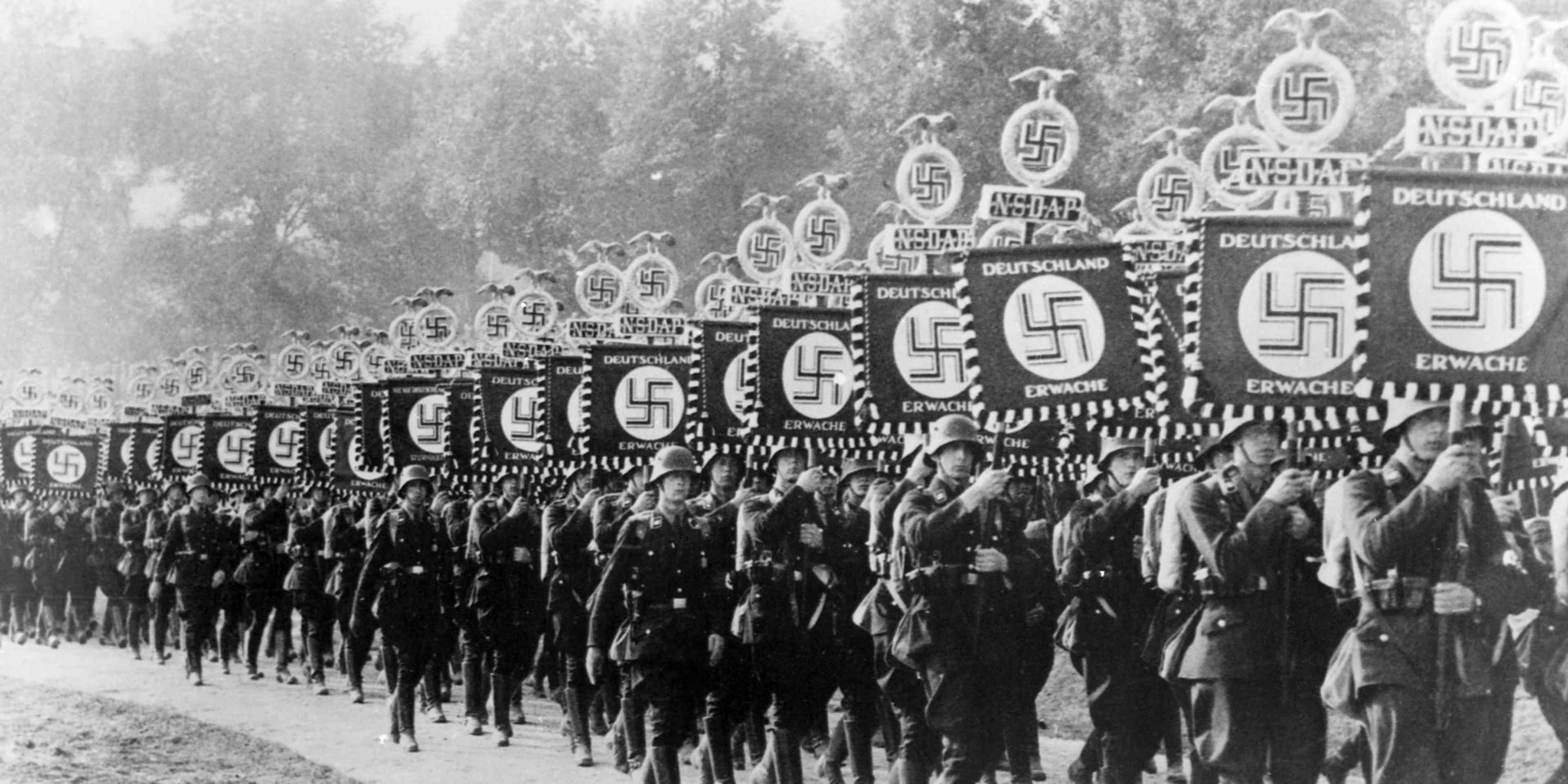 Marching SS Men Row upon row of SS members march down a road during the 1933 Nuremberg rally. The troops carry military standards with swastikas and the motto "Deutschland Erwache" (i.e. "Germany Awake").. (Photo by © CORBIS/Corbis via Getty Images)
