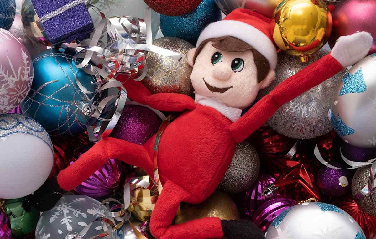 Elf on the shelf in a pile of baubles.