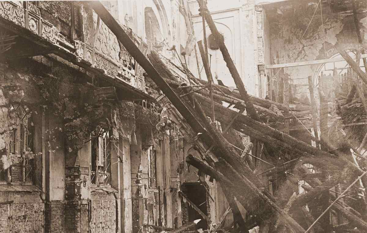 A dilapidated and damaged urban street scene, with debris and rubble scattered throughout the foreground, and the remains of damaged buildings and structures visible in the background.
