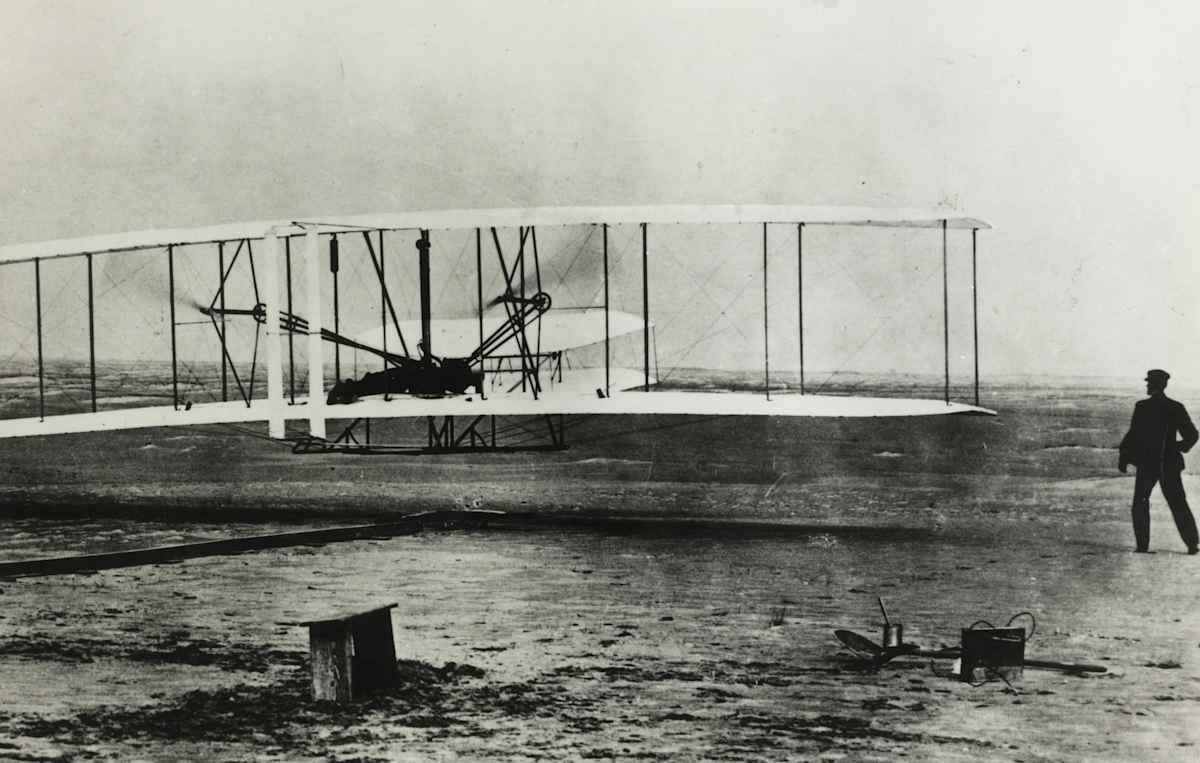 December 17th, 1903, Kittyhawk, North Carolina: The World's first flight with Orville Wright at the controls. His brother Wilbur is running at the side of the machine.