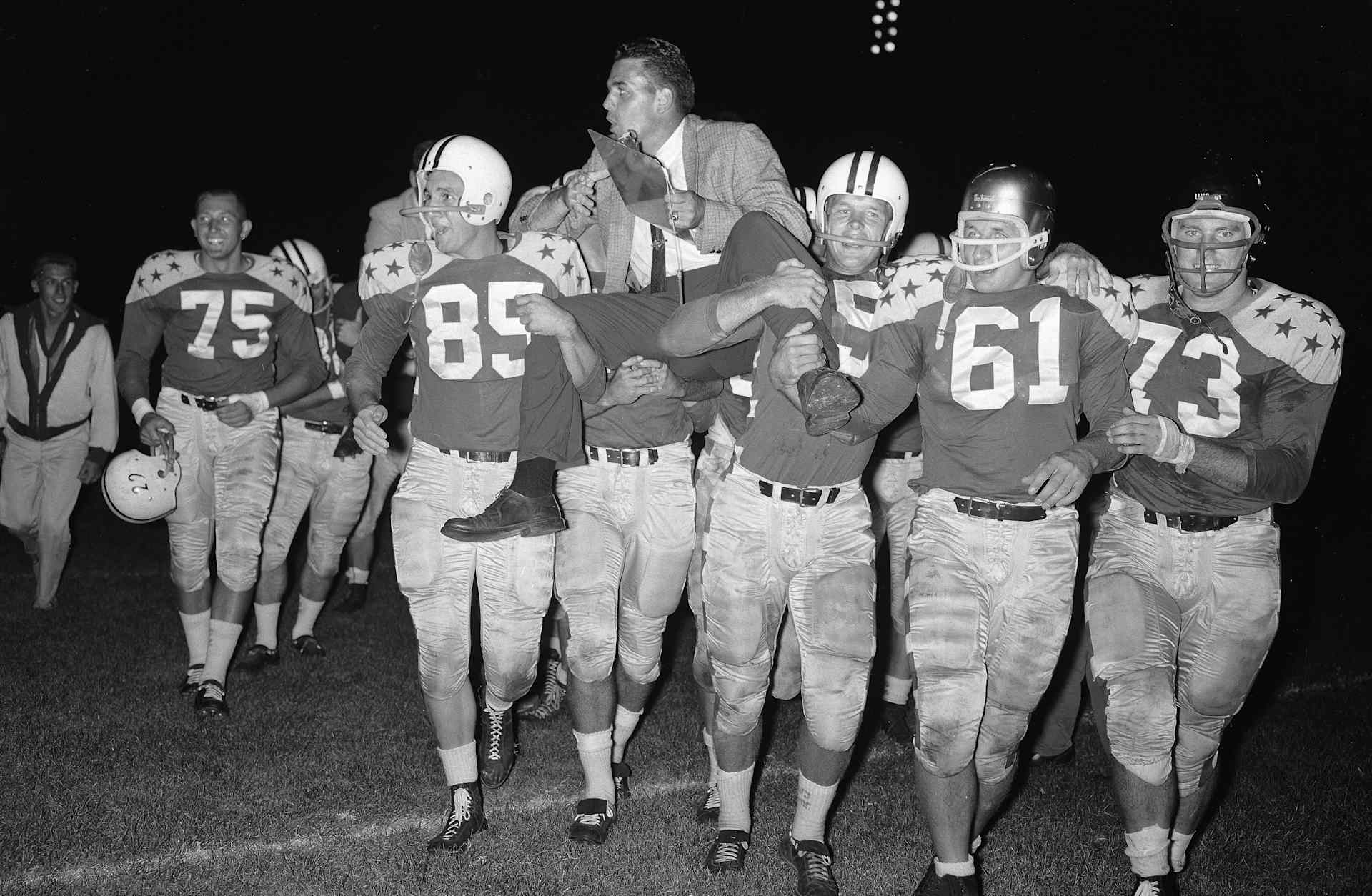 (Original Caption) Otto Graham, head coach of the College All-Stars, is carried from the field by victorious All Stars after 35-19 win over the Detroit Lions in the 25th annual All-Star game in Soldiers Filed here 8/15. Left to right: Wayne Walker, #75, Idaho; Bob Jewett, #85, Michigan State; Tony Stremic, #61, Navy and Charles Howley, #73, West Virginia.