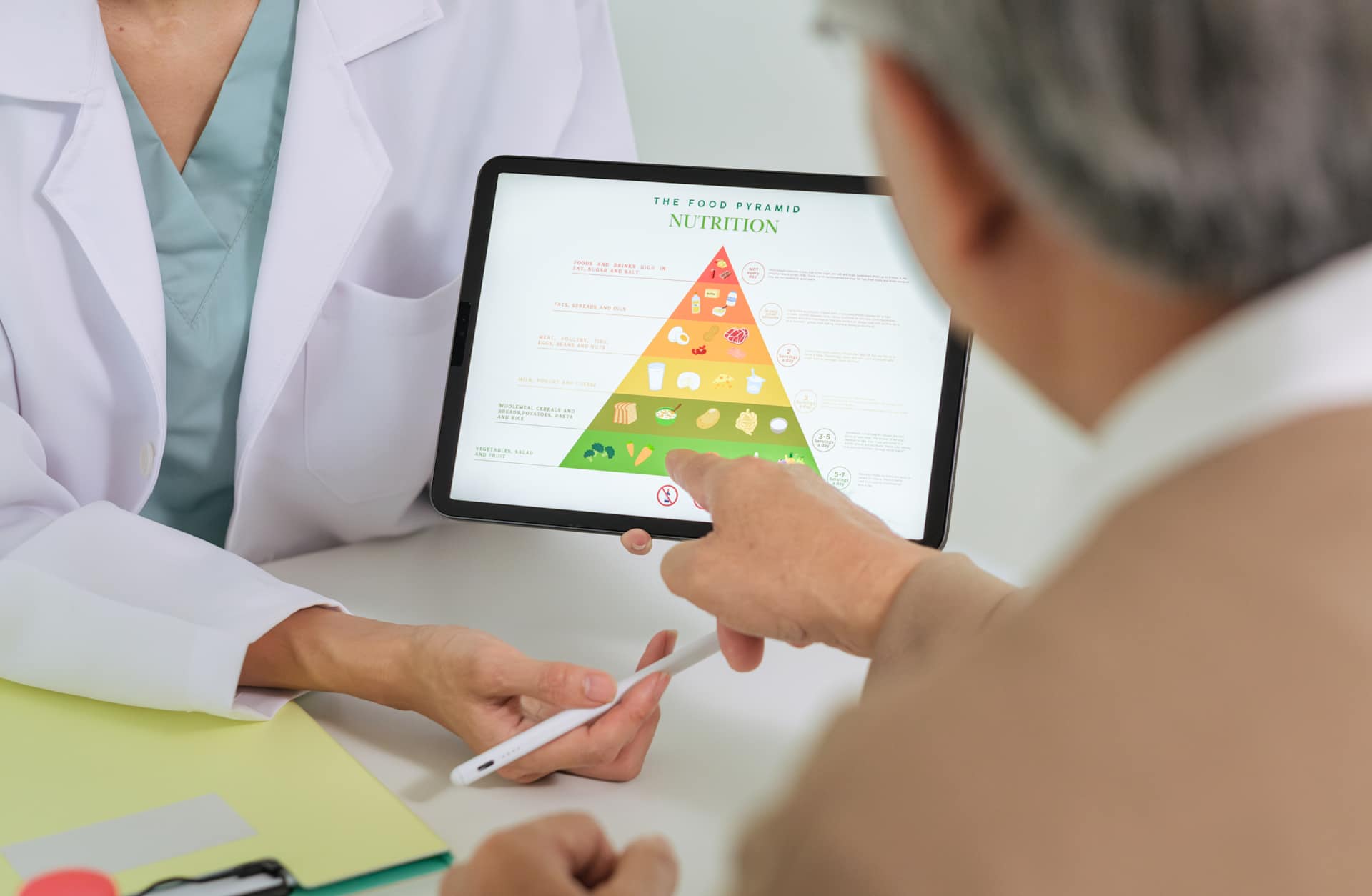 Doctor Explaining Healthy Eating and Food Pyramid to Senior Patient During Nutrition Counseling