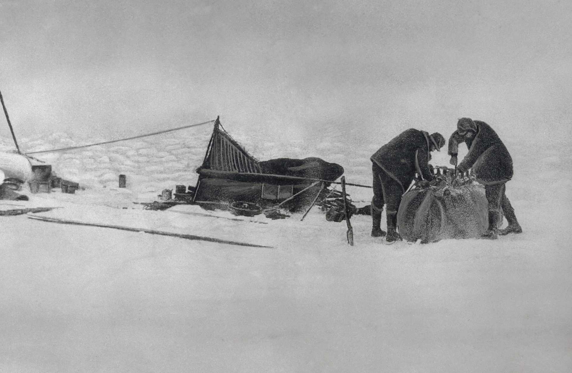 Two men packing up equipment in a snowy Arctic tundra.