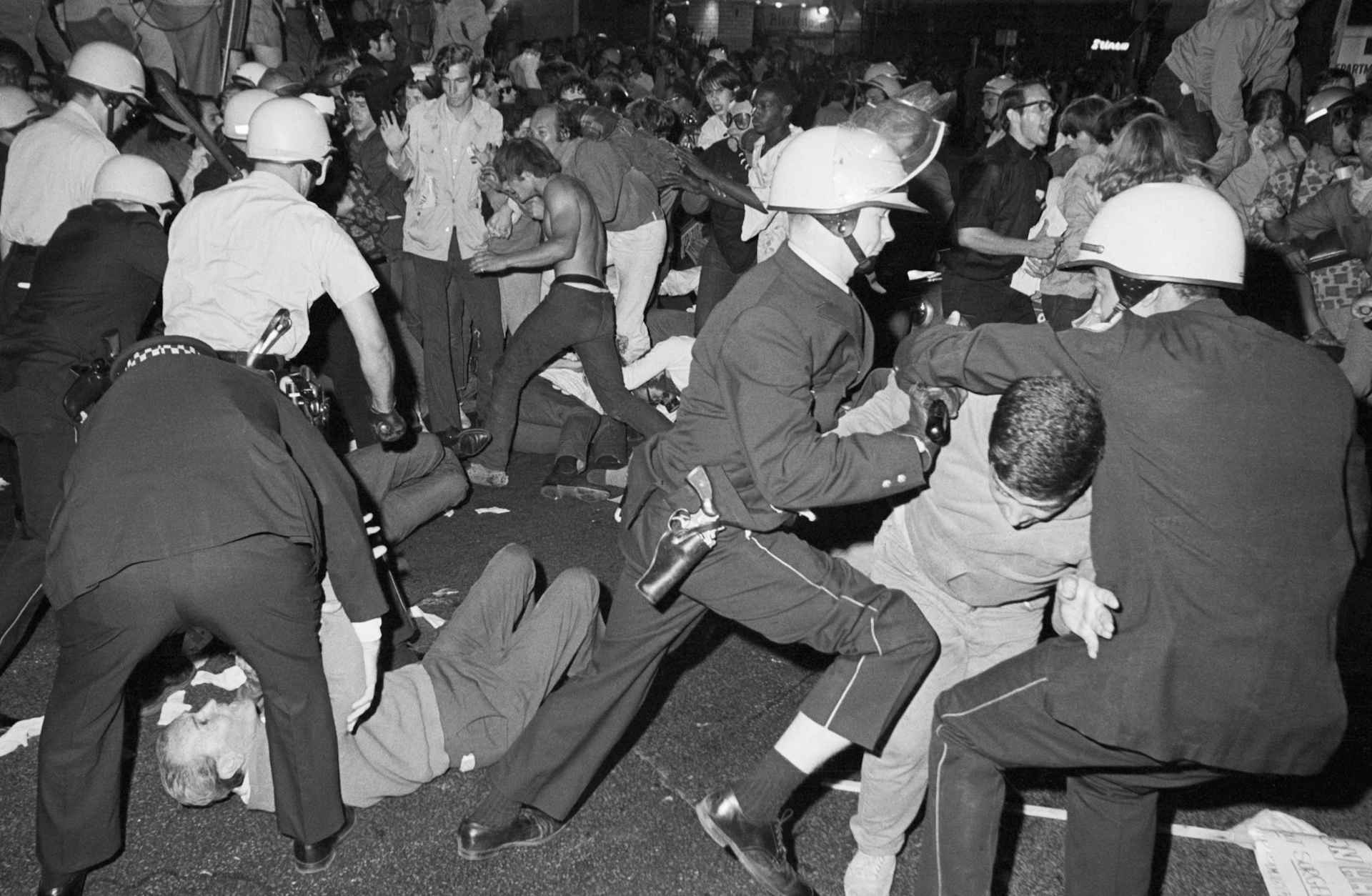 Police in white helmets actively trying to subdue a crowd of young people protesting the Vietnam war