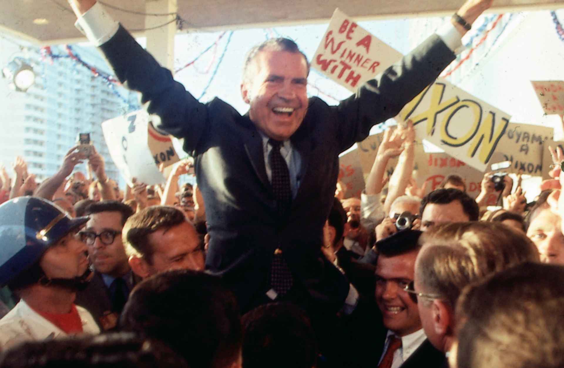 Richard Nixon flashes the peace sign