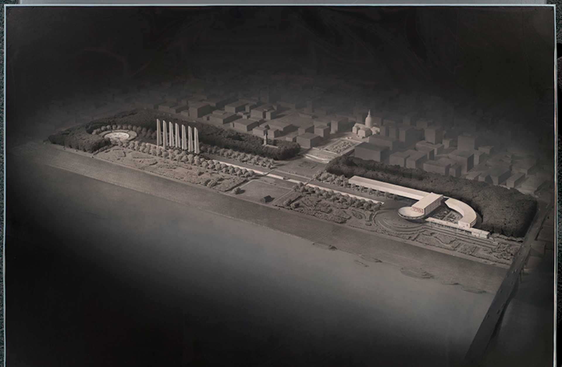 A large-scale architectural model or miniature depicting the Jefferson National Expansion Memorial, with intricate details and structures visible in the foreground and a cityscape in the background.