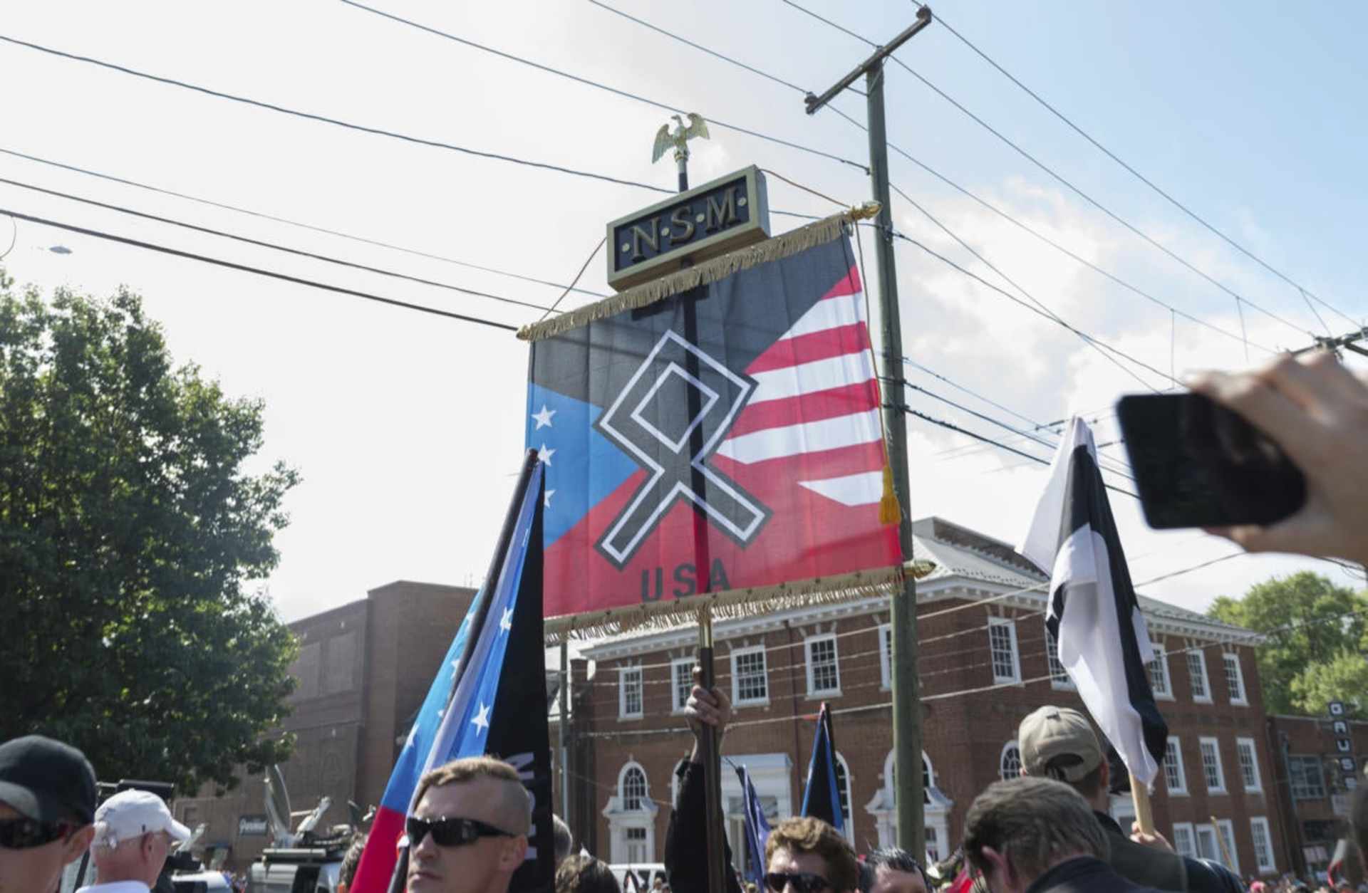 A man from an alt-right group carrying a flag with the othala rune before Virginia State Police ordered the evacuation by all parties and cancellation of the "Unite The Right" rally scheduled to take place in Emancipation Park, Charlottesville, Virginia, 2017.