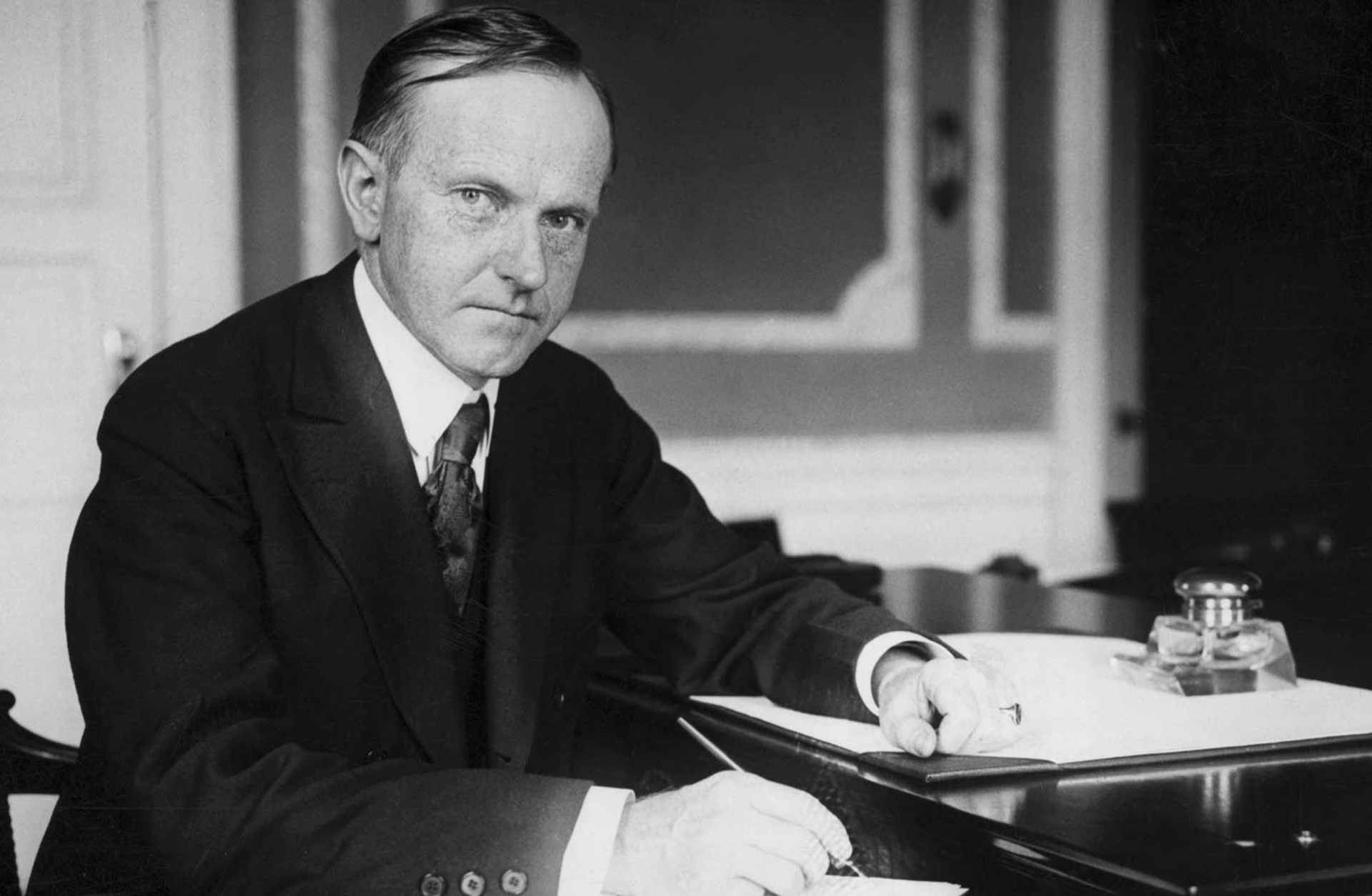 Calvin Coolidge (1872-1933), 30th President, sitting at his desk.