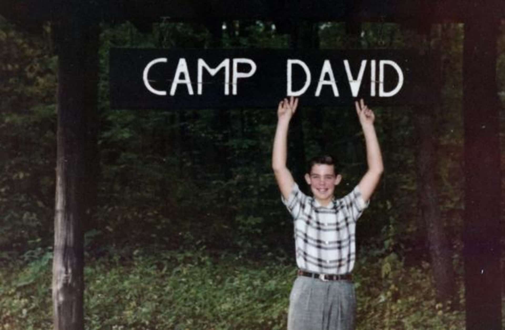 David Eisenhower, grandson of President Dwight D. Eisenhower, poses with Camp David sign, October 1960.