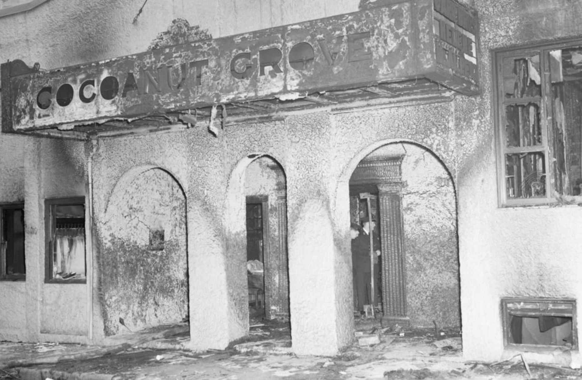 Firemen looking through the remains of Boston's Cocoanut Grove night club through the revolving doors leading to the tiny 10-foot-wide vestibule where stampeding guests were crushed and smothered as they tried to leave the burning club. (Credit: Bettmann Archive/Getty Images)