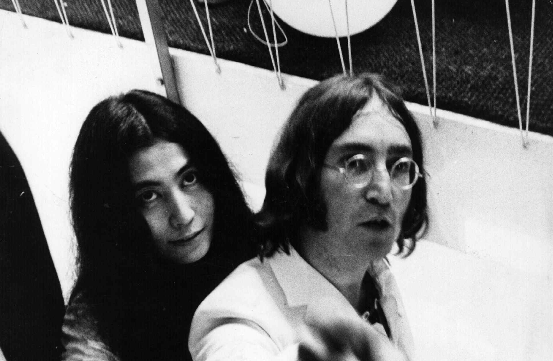 Beatles singer, songwriter and guitarist John Lennon (1940-1980) and his partner, artist Yoko Ono descend a staircase circa 1968.