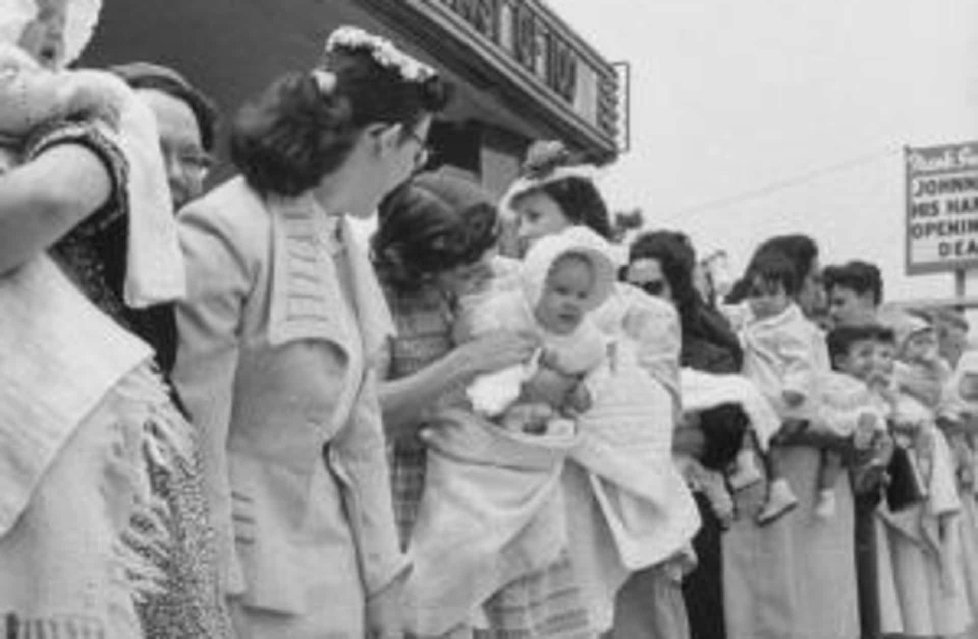 Mothers waiting in line with their children outside the Queen for a Day program