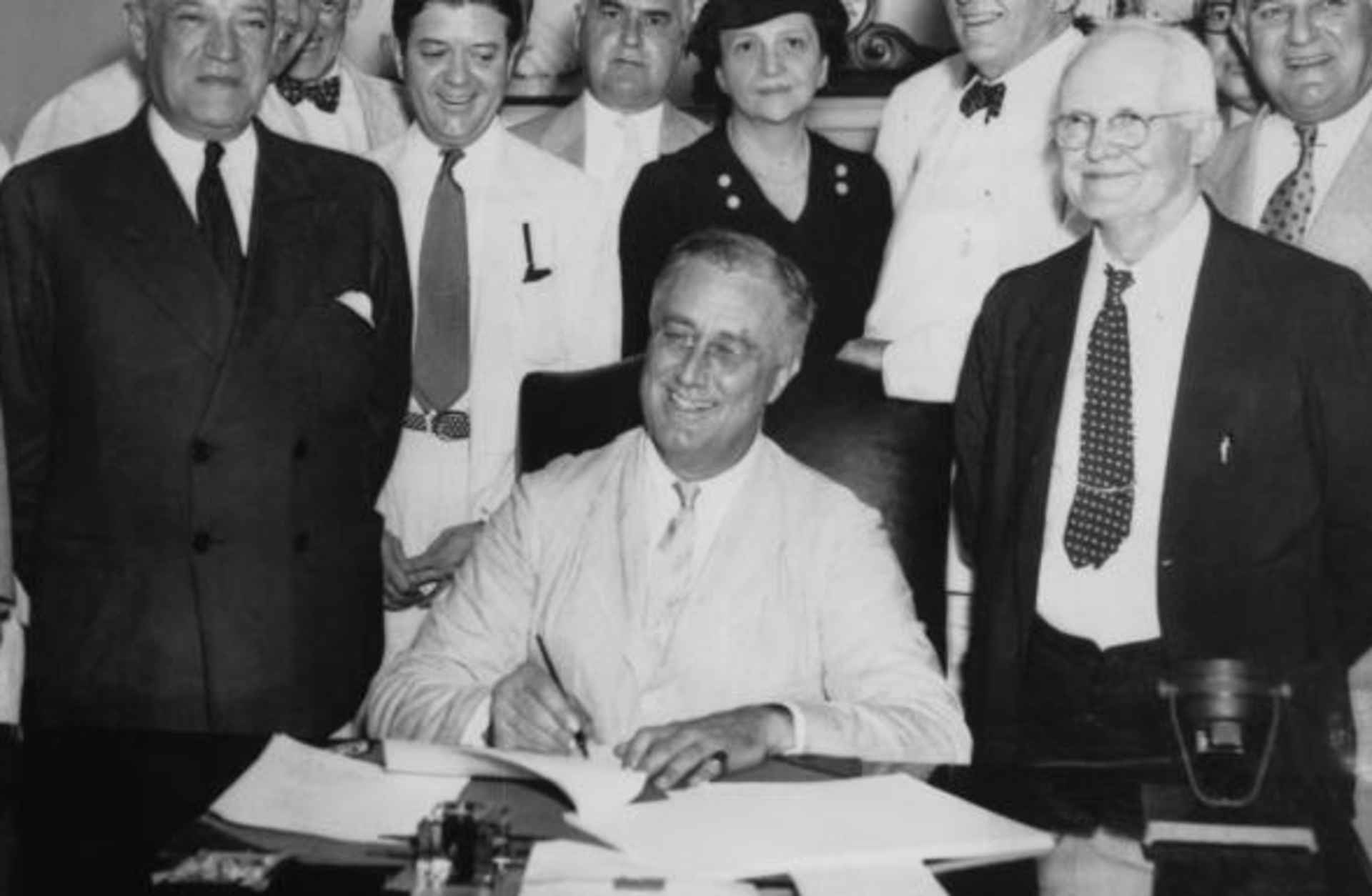 President Franklin D. Roosevelt signs the Social Security Act on 14th August 1935. From left to right, Robert Lee Doughton, chairman of the House Ways and Means Committee, Edwin E. Witte, Director of the President's Social Security Committee, with Senator Robert F. Wagner, co-author of the bill behind him, Senator Robert La Follette, Senator Augustine Lonergan, Labor Secretary Frances Perkins, Senator William H. King, Rep. David John Lewis, co-author of the bill and Senator Joseph F. Guffey.