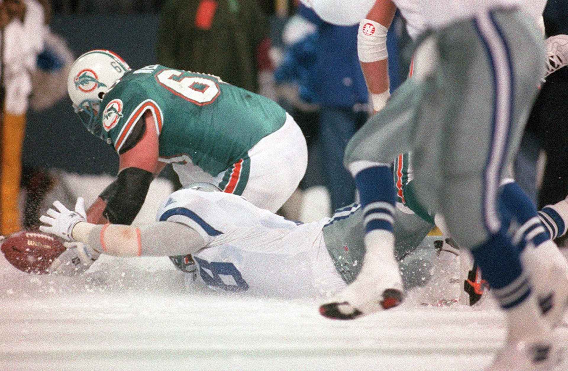 In this Nov. 25, 1993 file photo, The Dallas Cowboys and Miami Dolphins meet on the icy field of Texas Stadium for an NFL football game on Thanksgiving Day in Irving, Texas. After blocking a field goal attempt with 15 seconds left in a snowy game, the Cowboys appear to have the win. But Leon Lett slides into the ball, which is now live; the Dolphins recover and Pete Stoyanovich kicks a game-winning 20-yard field goal with 3 seconds left. The Dolphins won 16-14. (AP Photo/Fort Worth Star-Telegram, File)