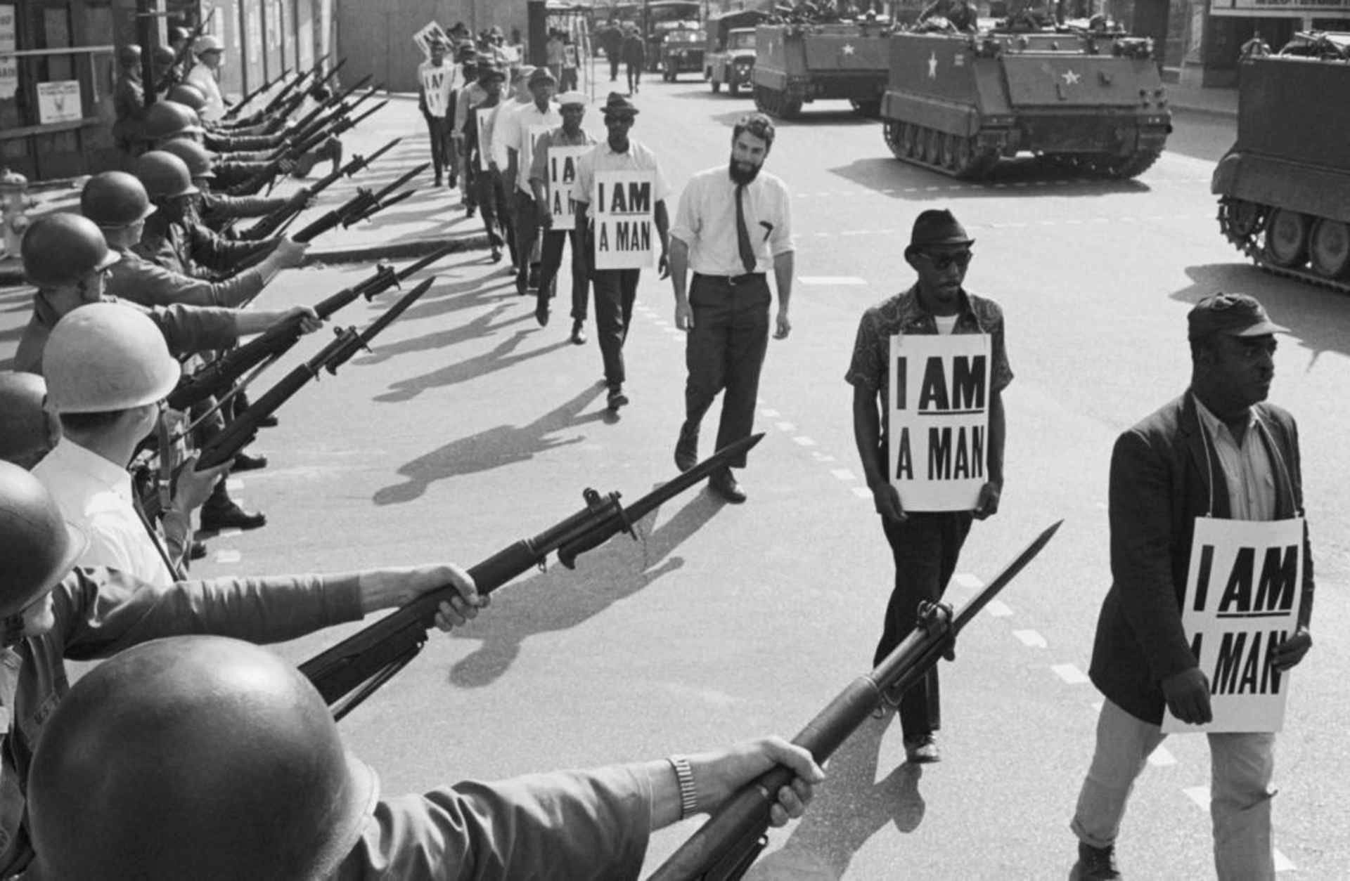 U.S. National Guard troops blocking off a street while striking Memphis sanitation workers march by, wearing placards reading, 'I Am A Man' on March 29, 1968. King was killed on the eve of a second march to support the sanitation workers. (Credit: Bettmann Archive/Getty Images)
