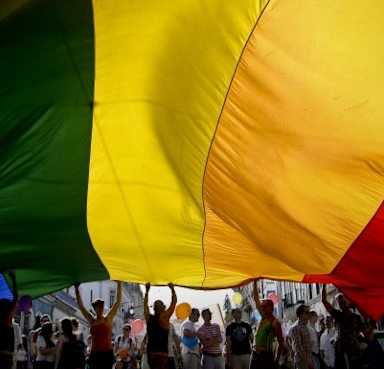 People wave a giant rainbow flag during a Gay Pride Parade. (Credit: Patricia De Melo Moreira/AFP/Getty Images)