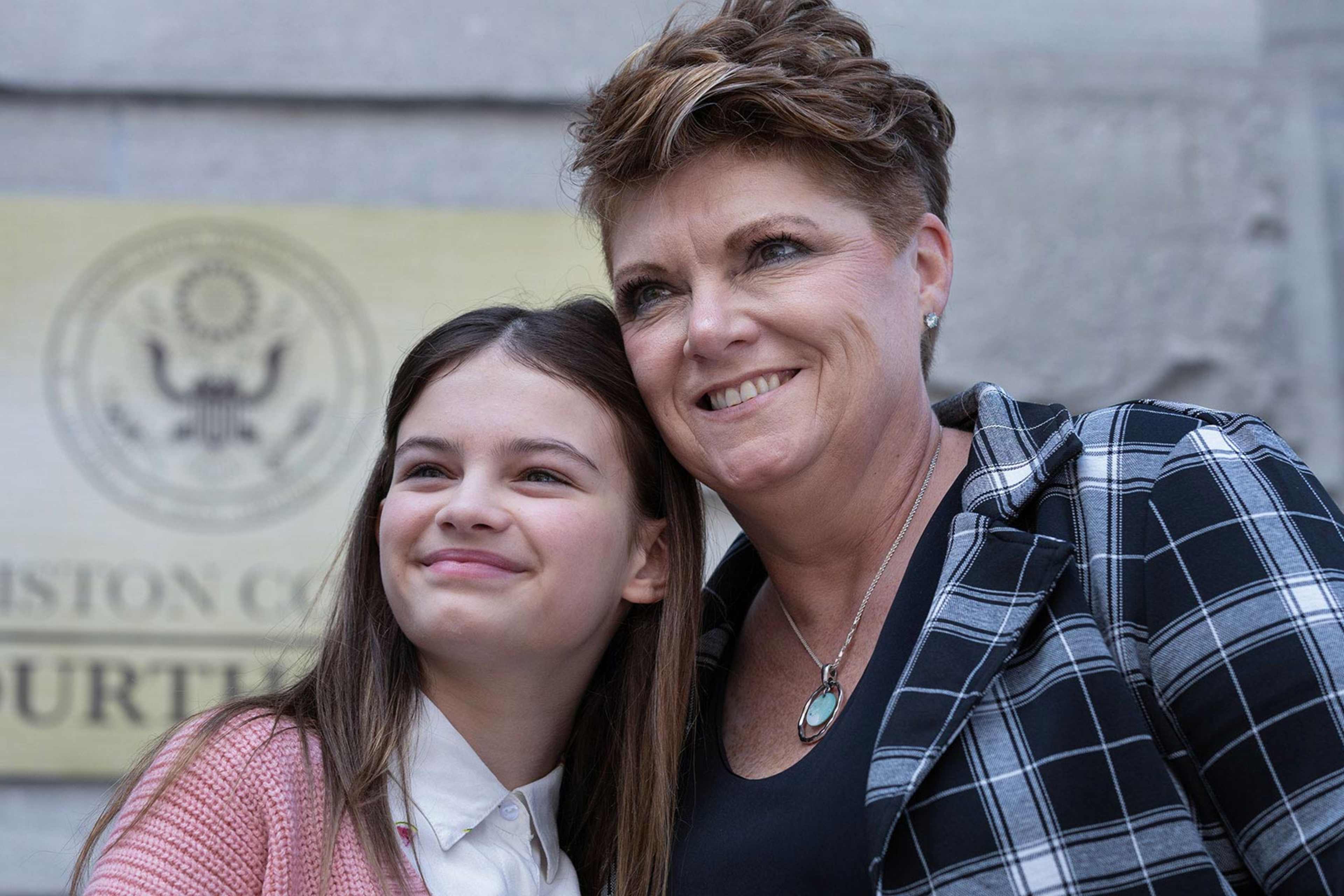 The image shows two women, one older and one younger, standing together in front of a building with the text "Elliston County Courthouse" visible in the background.