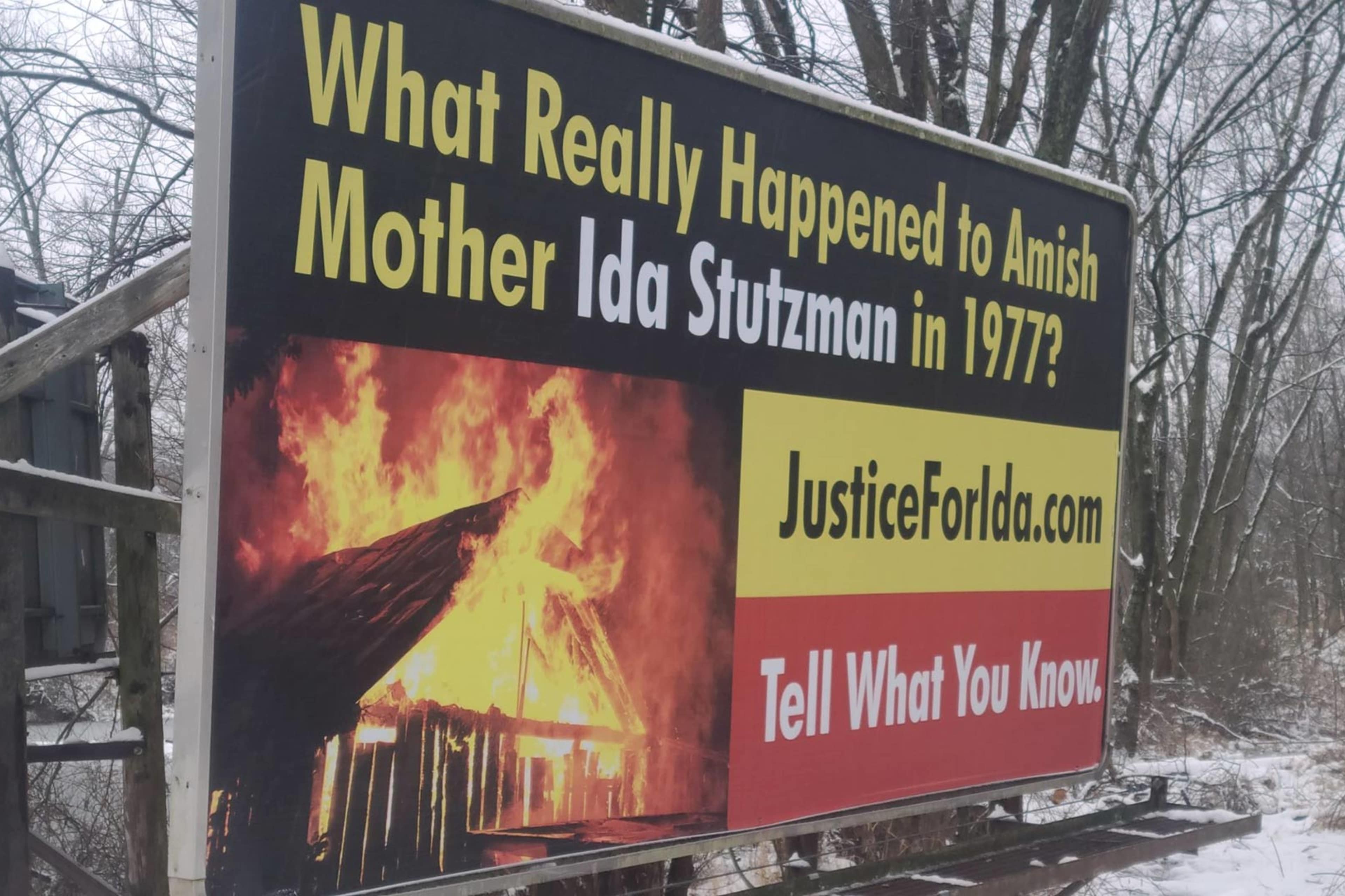 The image shows a large billboard with a dramatic image of a burning building and the text "What Really Happened to Amelia Earhart's Mother Too Shocking in 1937?" along with a website address.