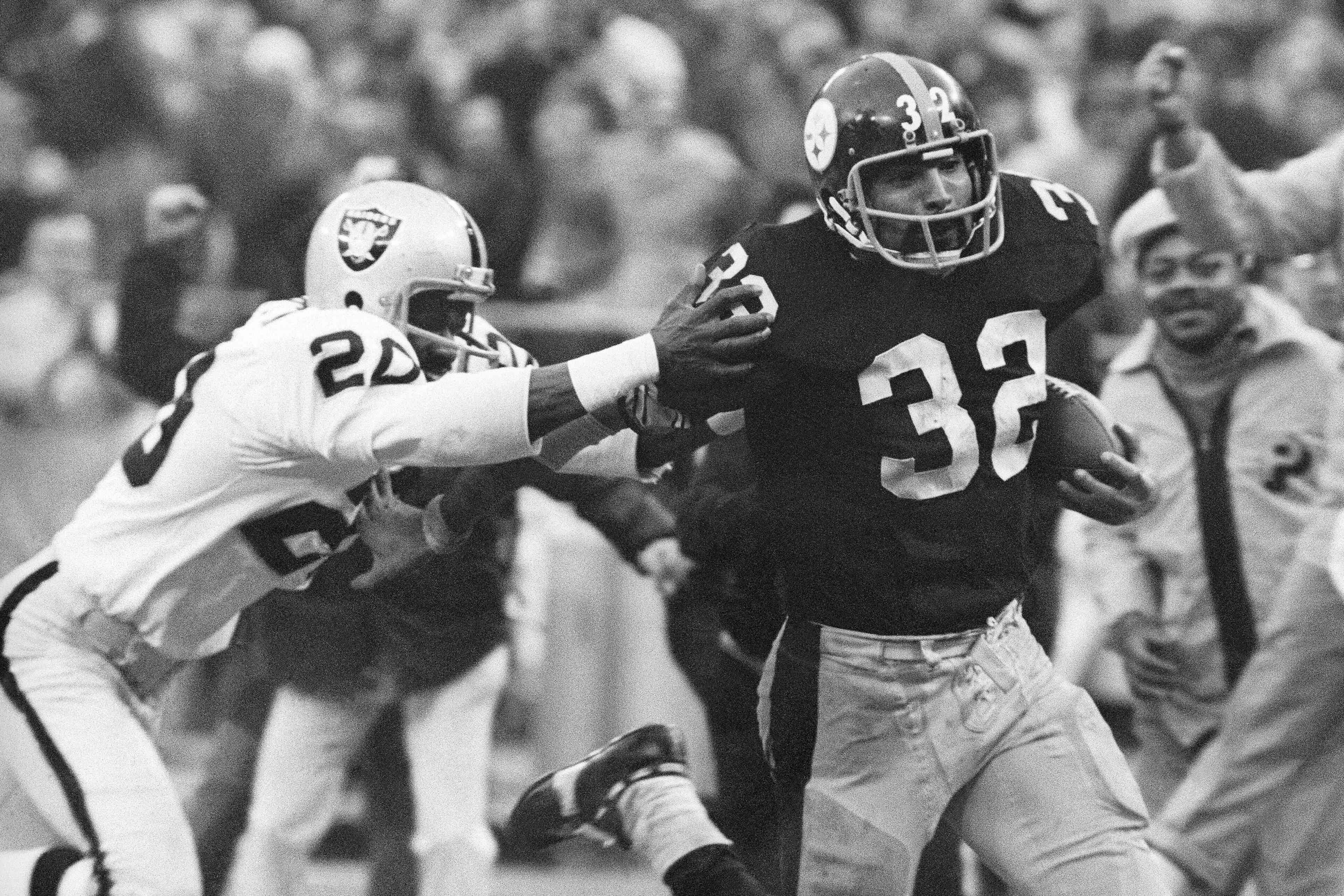 In this Dec. 23, 1972, file photo, Pittsburgh Steelers' Franco Harris (32) eludes a tackle by Oakland Raiders' Jimmy Warren as he runs 42-yards for a touchdown after catching a deflected pass during an AFC Divisional NFL football playoff game in Pittsburgh. Harris' scoop of a deflected pass and subsequent run for the winning touchdown, forever known as the "Immaculate Reception." (AP Photo/Harry Cabluck, File)