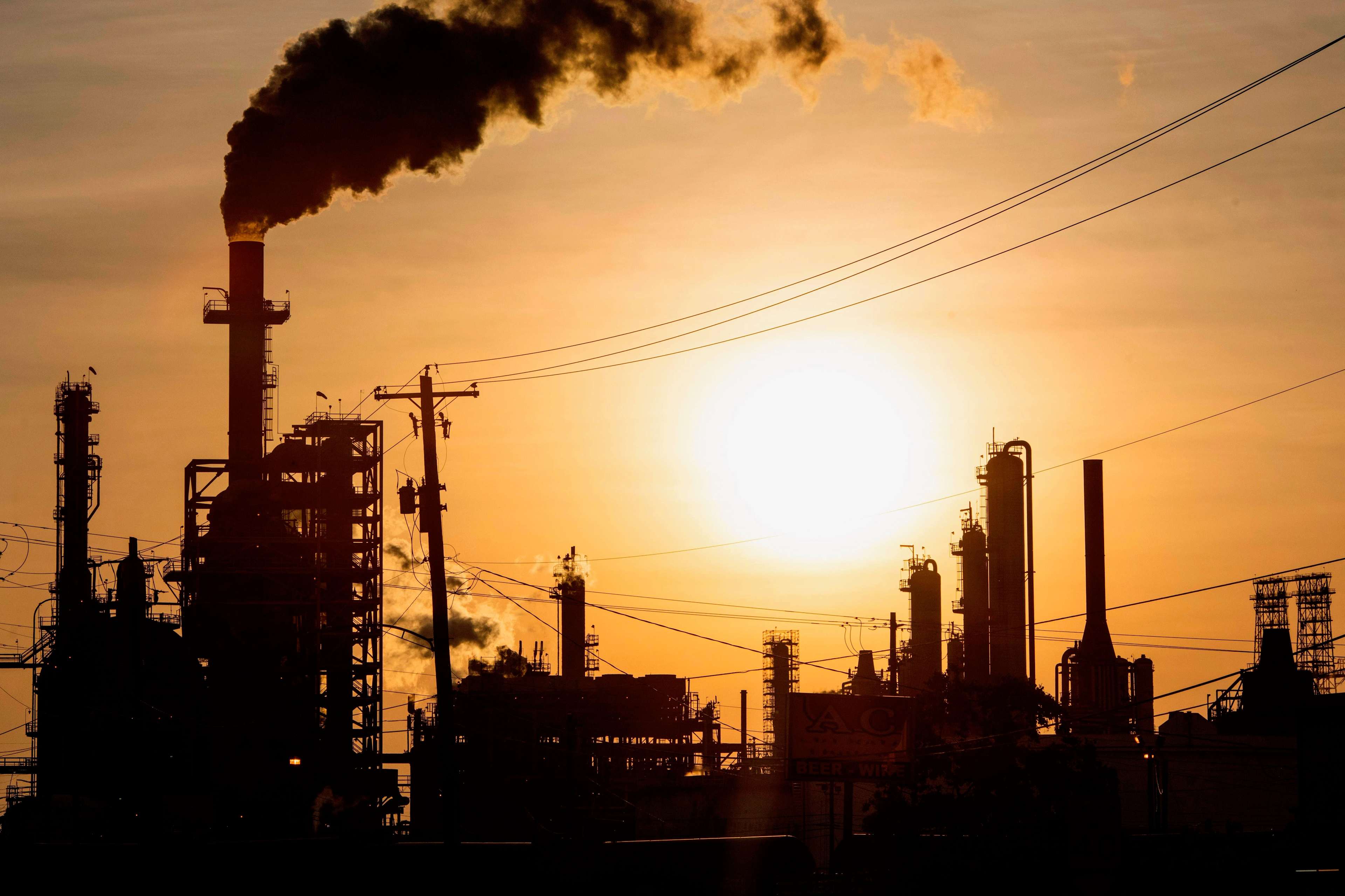 TOPSHOT - The sun sets behind smoke rising from the LyondellBasell-Houston Refining plant in Houston, Texas, on April 20, 2020. - US oil prices crashed to unprecedented lows on April 20 as futures in New York ended in negative territory for the first time amid a devastating supply glut that has forced traders to pay others to take the crude off their hands. (Photo by Mark Felix / AFP) (Photo by MARK FELIX/AFP /AFP via Getty Images)