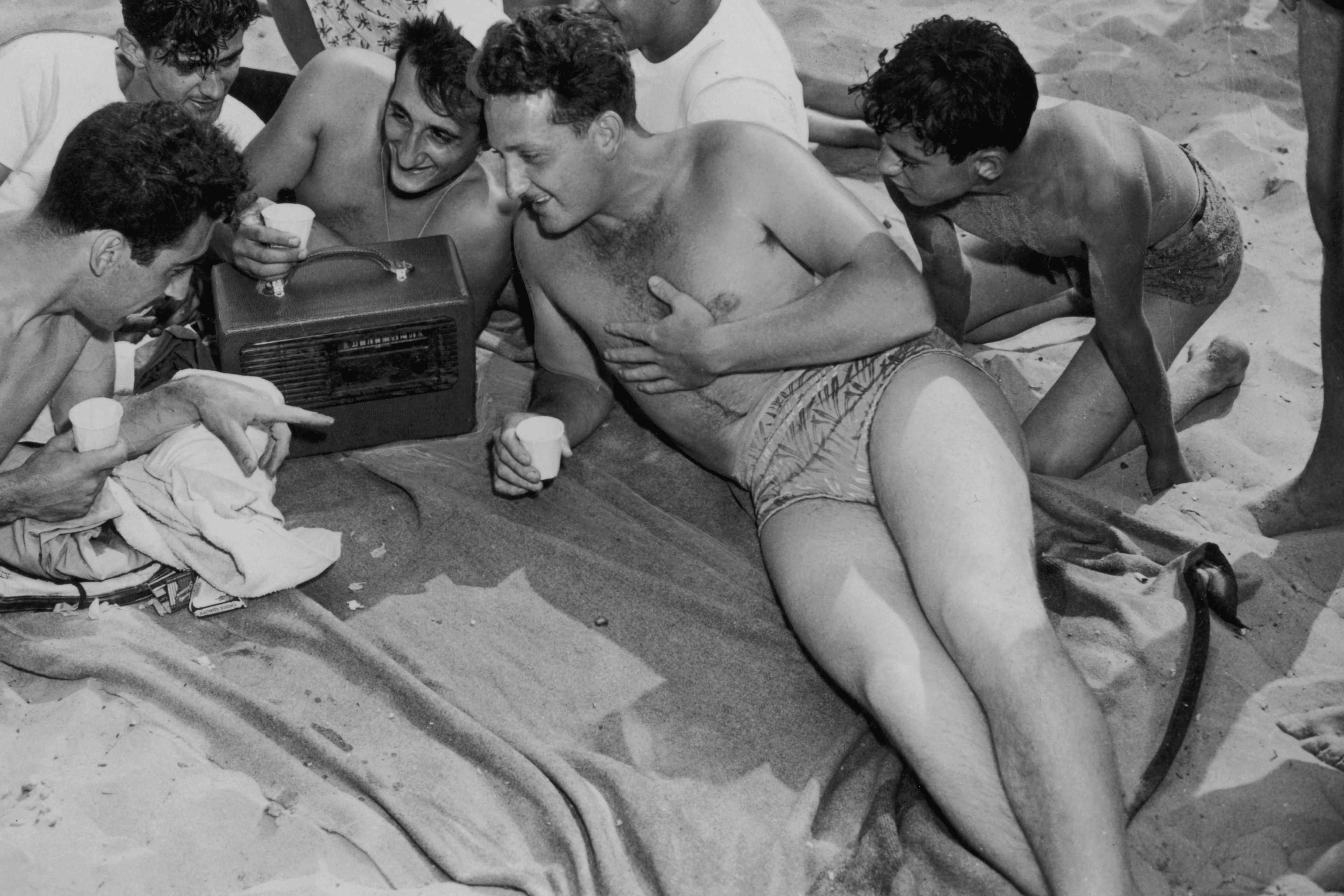 A group of young people listening to a portable radio on the beach at Coney Island, New York, July 1947.