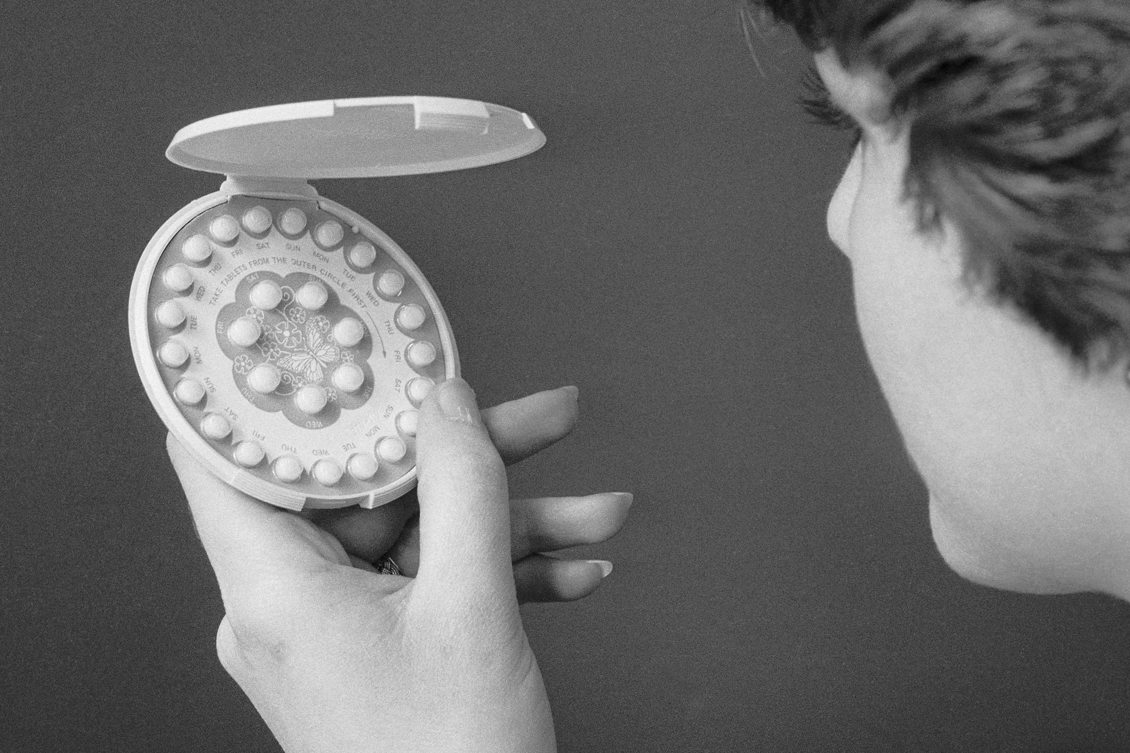 A 1976 photo of a woman holding a pack of birth control pills.