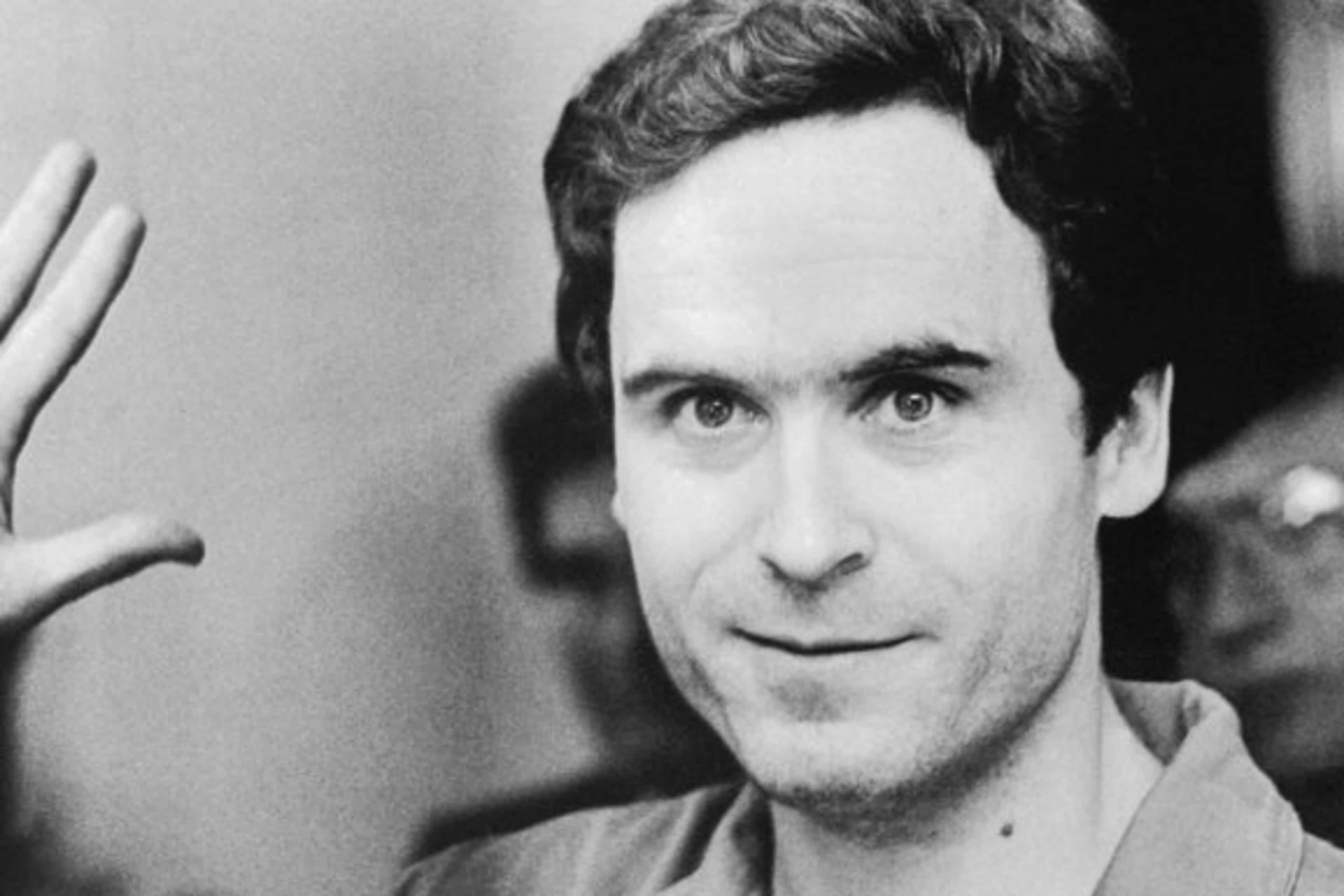 Serial Murderer Theodore "Ted" Bundy walks forward and waves to TV camera as his indictment for the January murders of Lisa Levy and Margaret Bowman is read at the Leon County Jail.