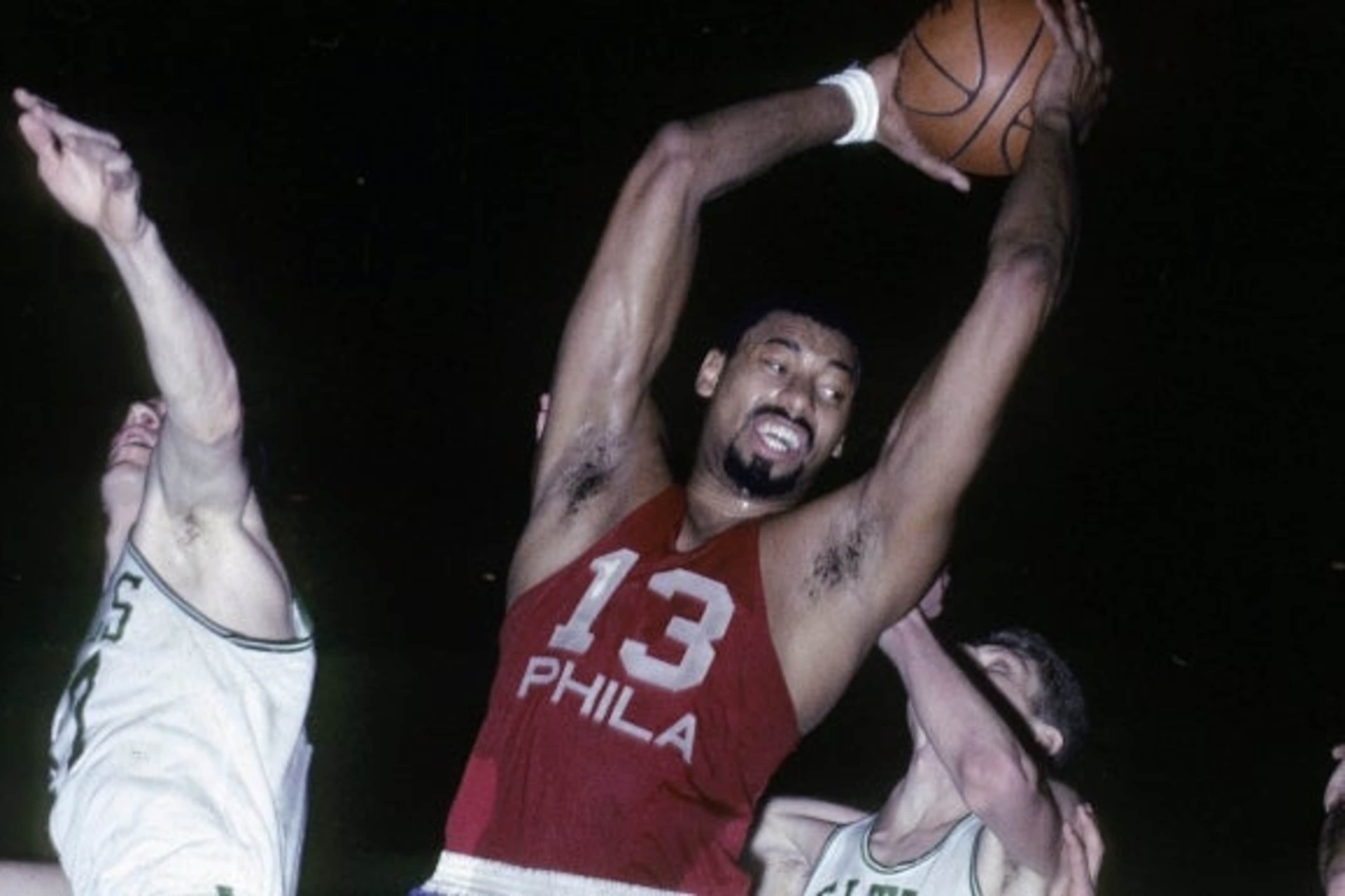 Wilt Chamberlain of the Philadelphia 76ers pulls down a rebound against the Boston Celtics during a mid-1960s game at Boston Garden. (Credit: Focus on Sport/Getty Images)