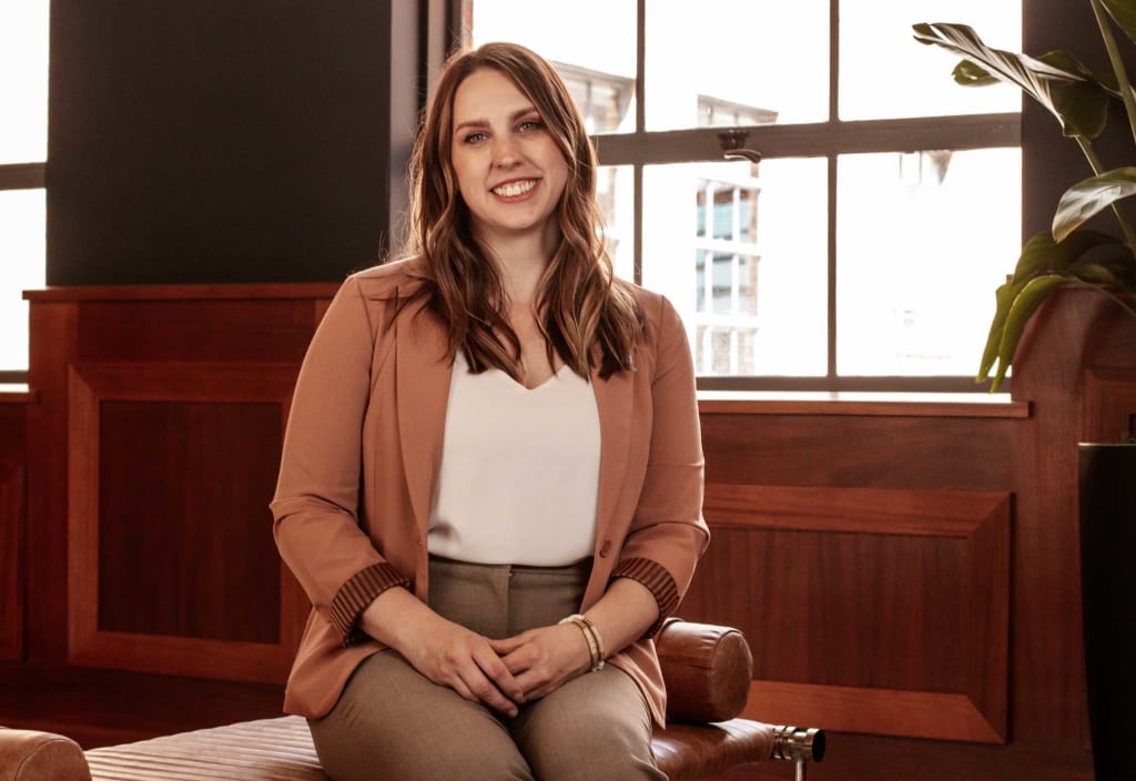 woman in brown jacket sitting and smiling