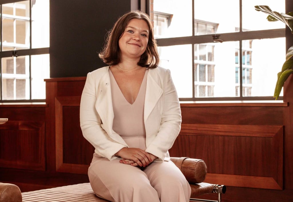 woman in white blazer sitting and smiling
