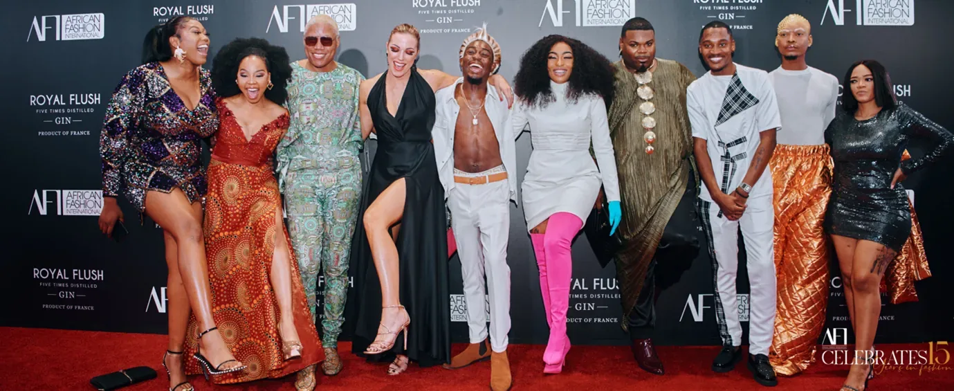 A group of men and women standing in a line on a red carpet with a black and white background