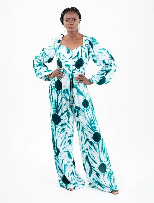 Model wearing Sisters of Africa Tie Dye jumpsuit made in Senegal. Green and white, sweetheart neckline, long sleeves jumpsuit with belt is perfect if you are thinking of festival outfit ideas.