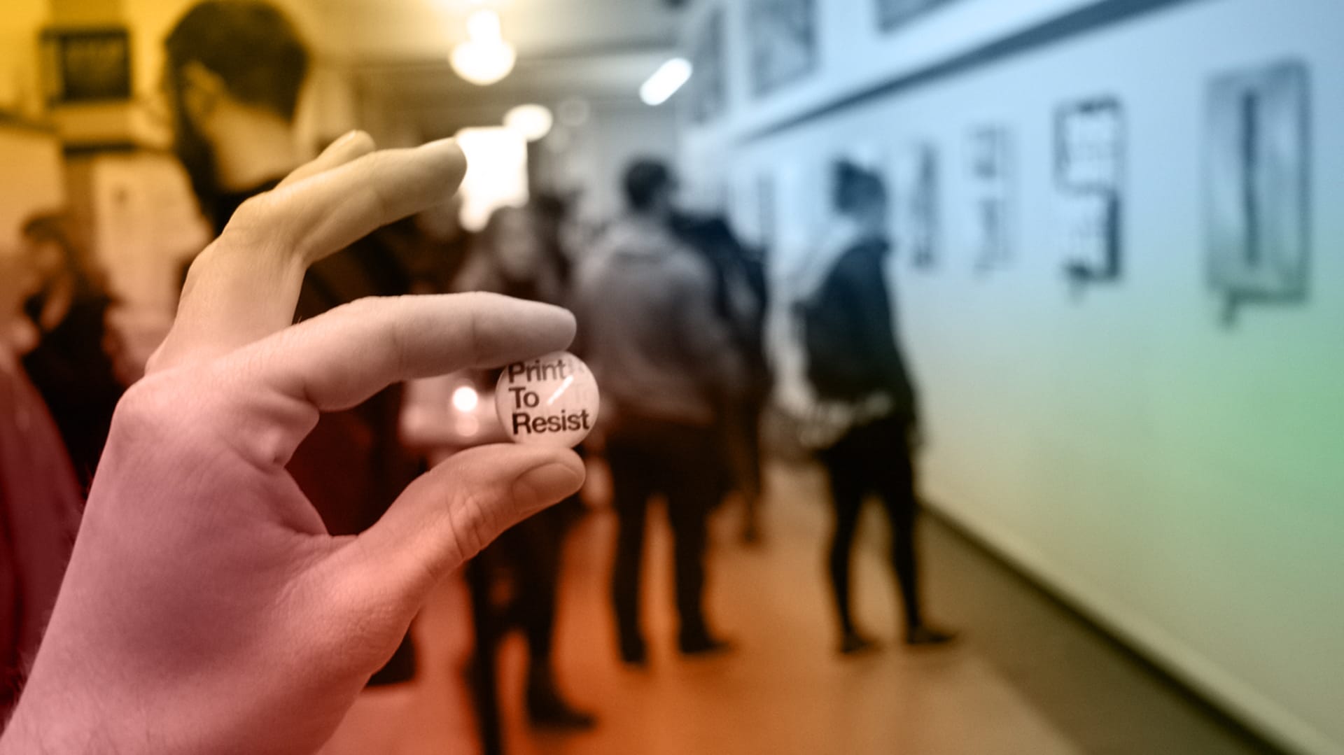 person holding a pin that reads print to resist