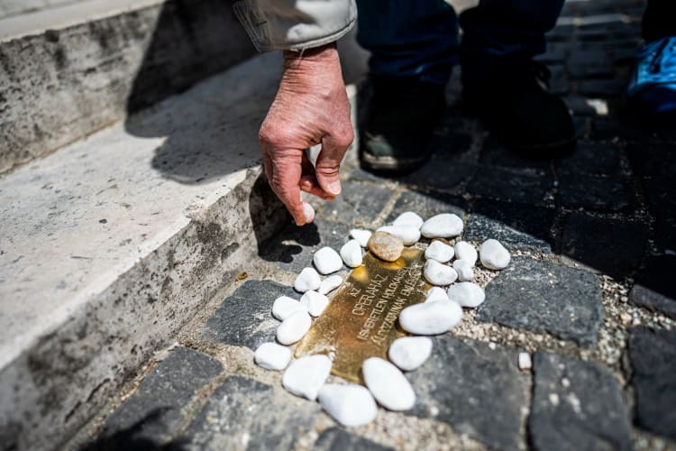Követ helyez el egy résztvevő a botlatókövek avatásán