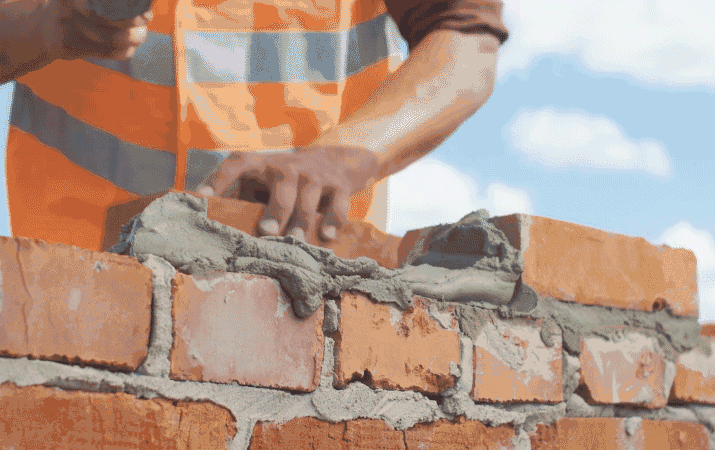 gif maçon qui construit un mur de briques