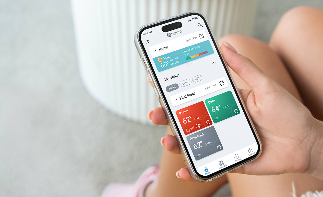 Person holding a smartphone with the Airzone Cloud app open, showing the home screen.