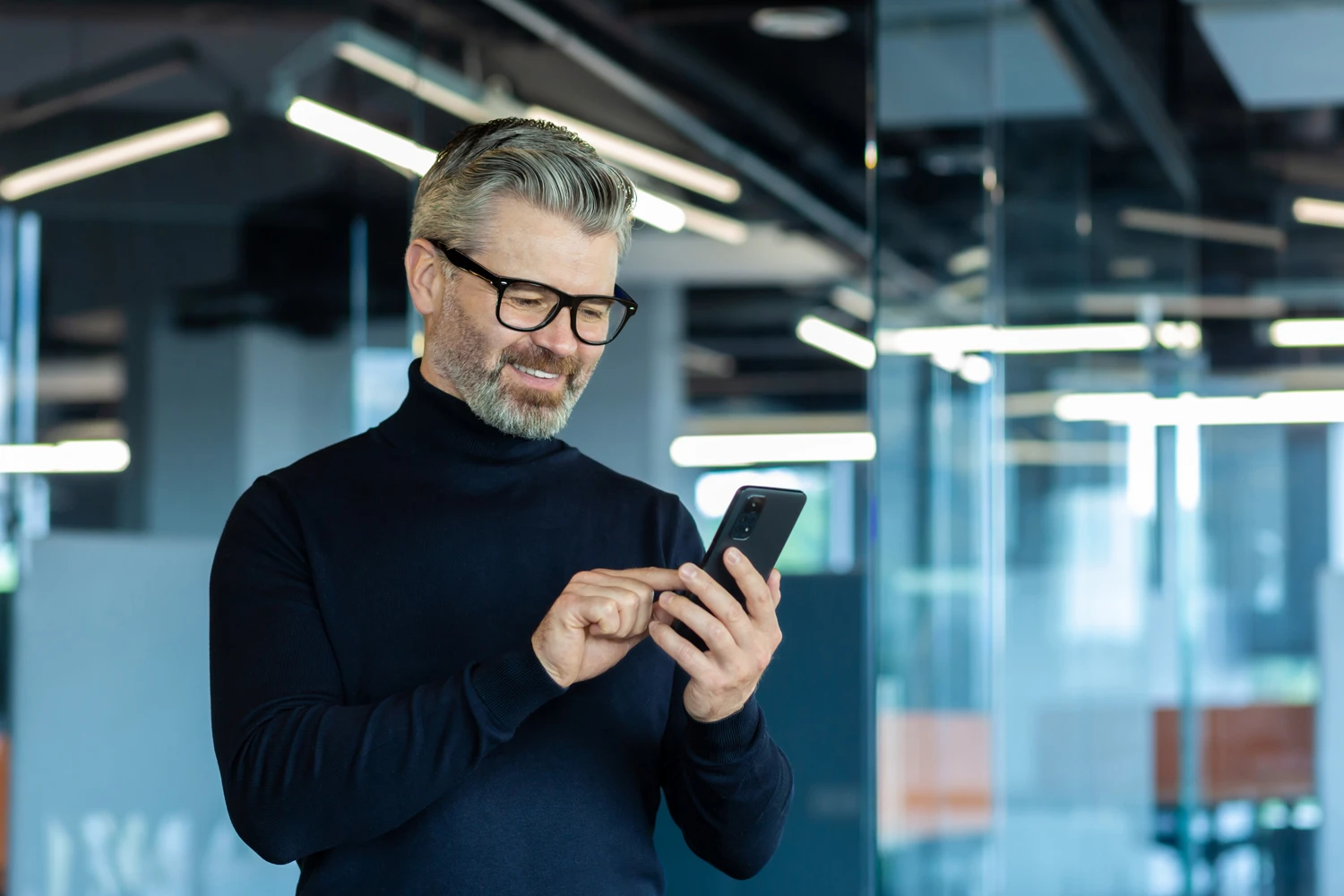 Hand holding a mobile phone displaying energy consumption graphs