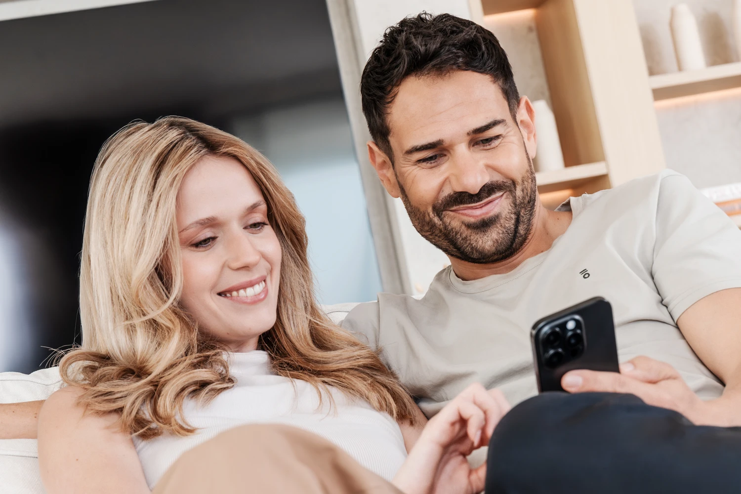 Young couple smiling while looking at the app on their smartphone Young couple smiling while looking at the app on their smartphone