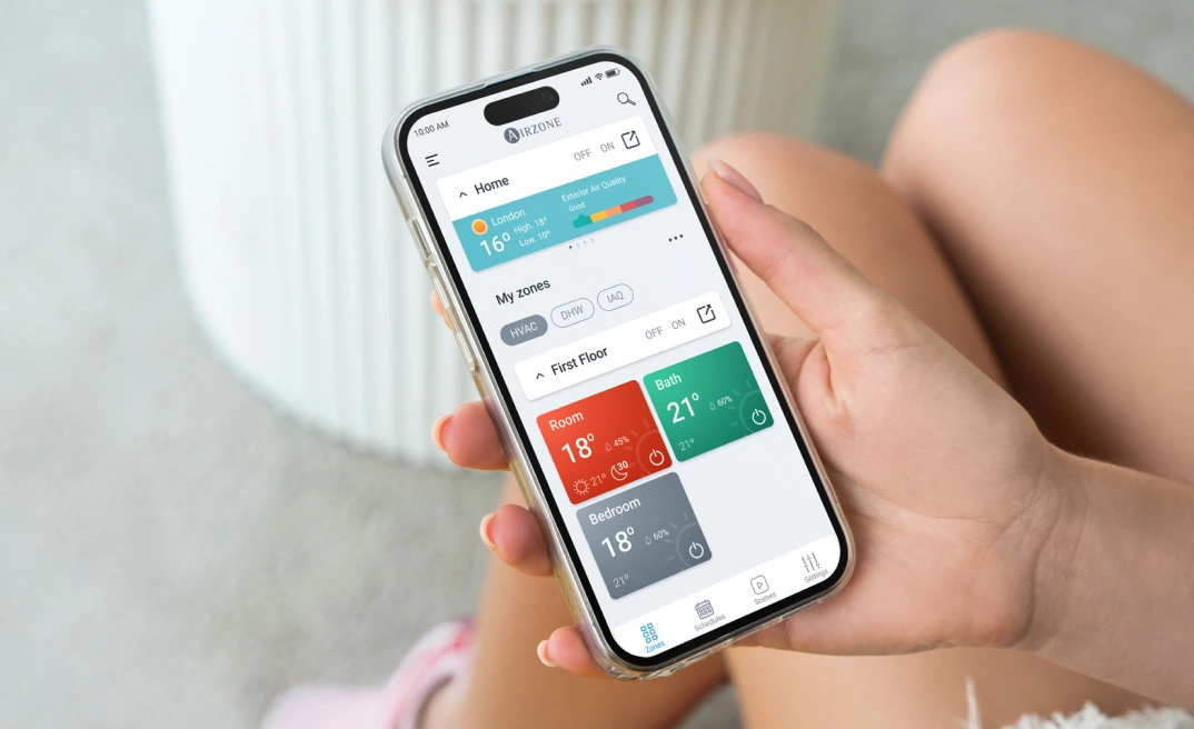 Person holding a smartphone with the Airzone Cloud app open, showing the home screen.
