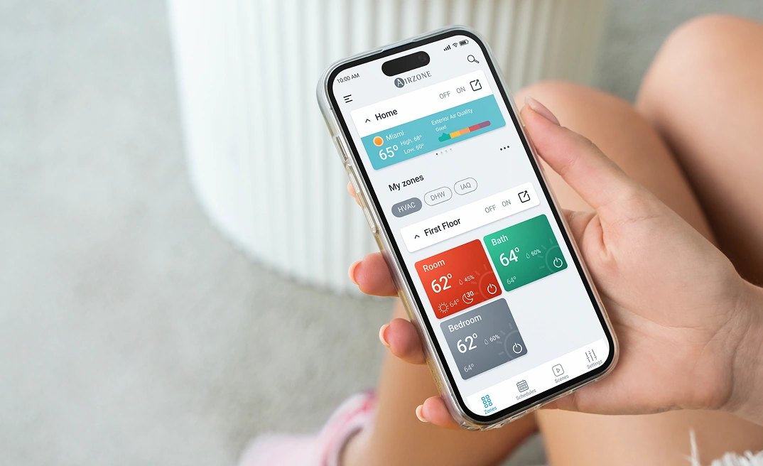 Person holding a smartphone with the Airzone Cloud app open, showing the home screen.