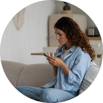 Woman using a mobile phone while sitting comfortably on a sofa