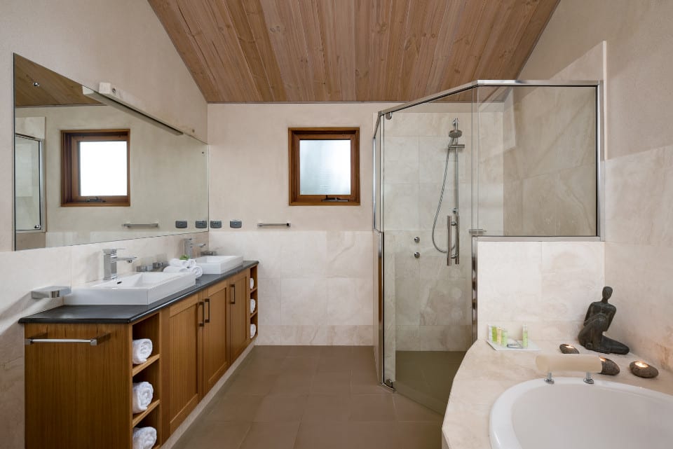 A wonderfully bright white tiled bathroom with spa, shower and wooden vanity.