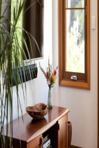 Native flowers in a vase on a wooden cabinet.