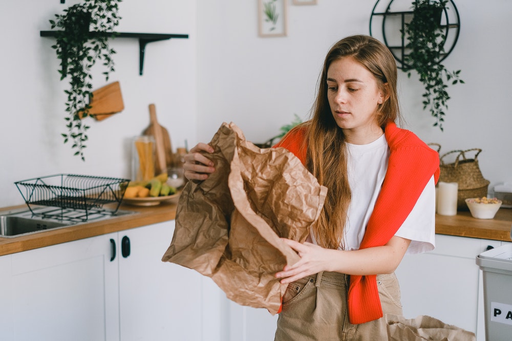 Woman folding was paper in the kitchen.