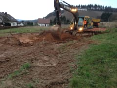 A digger digging soil on a plot of land.